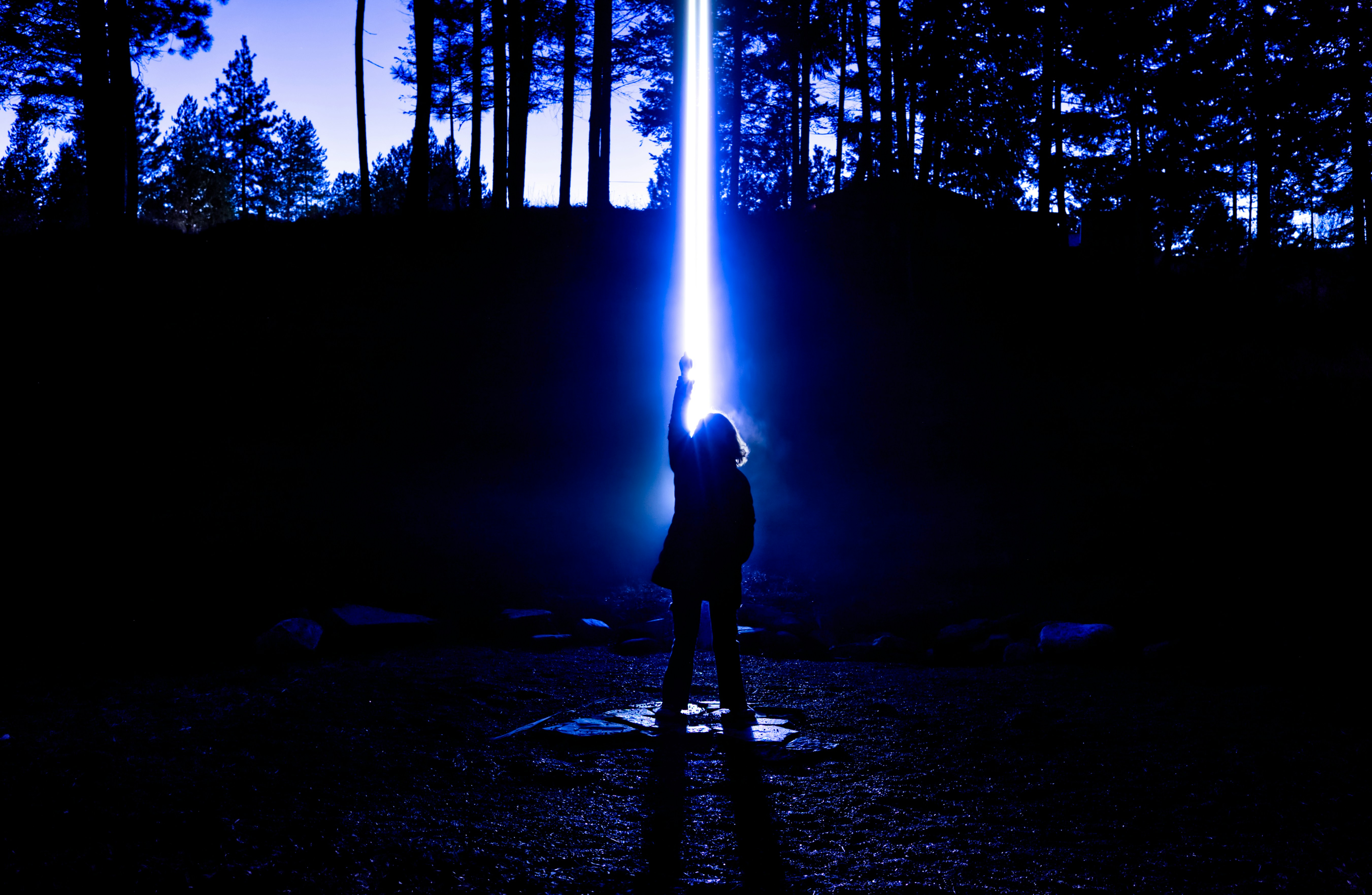 Person reaching for a bright blue light beam.
