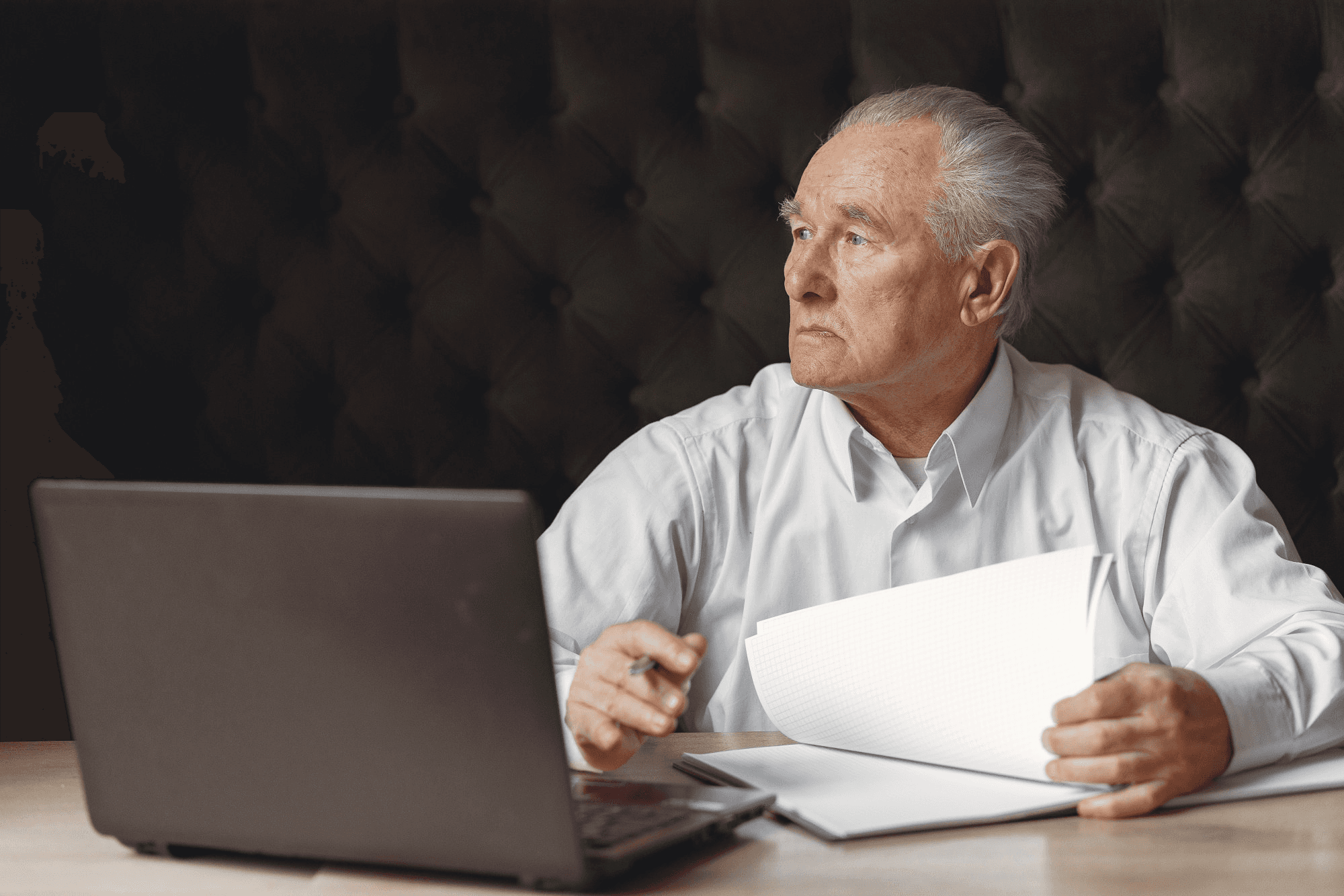 A person with curly hair sits at a desk, working on a laptop in a cozy, well-lit environment.