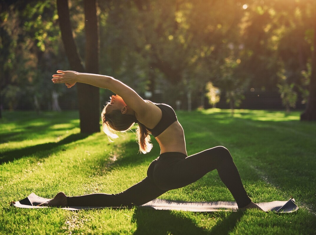 flexible woman doing yoga for weight loss in a sunny park outside