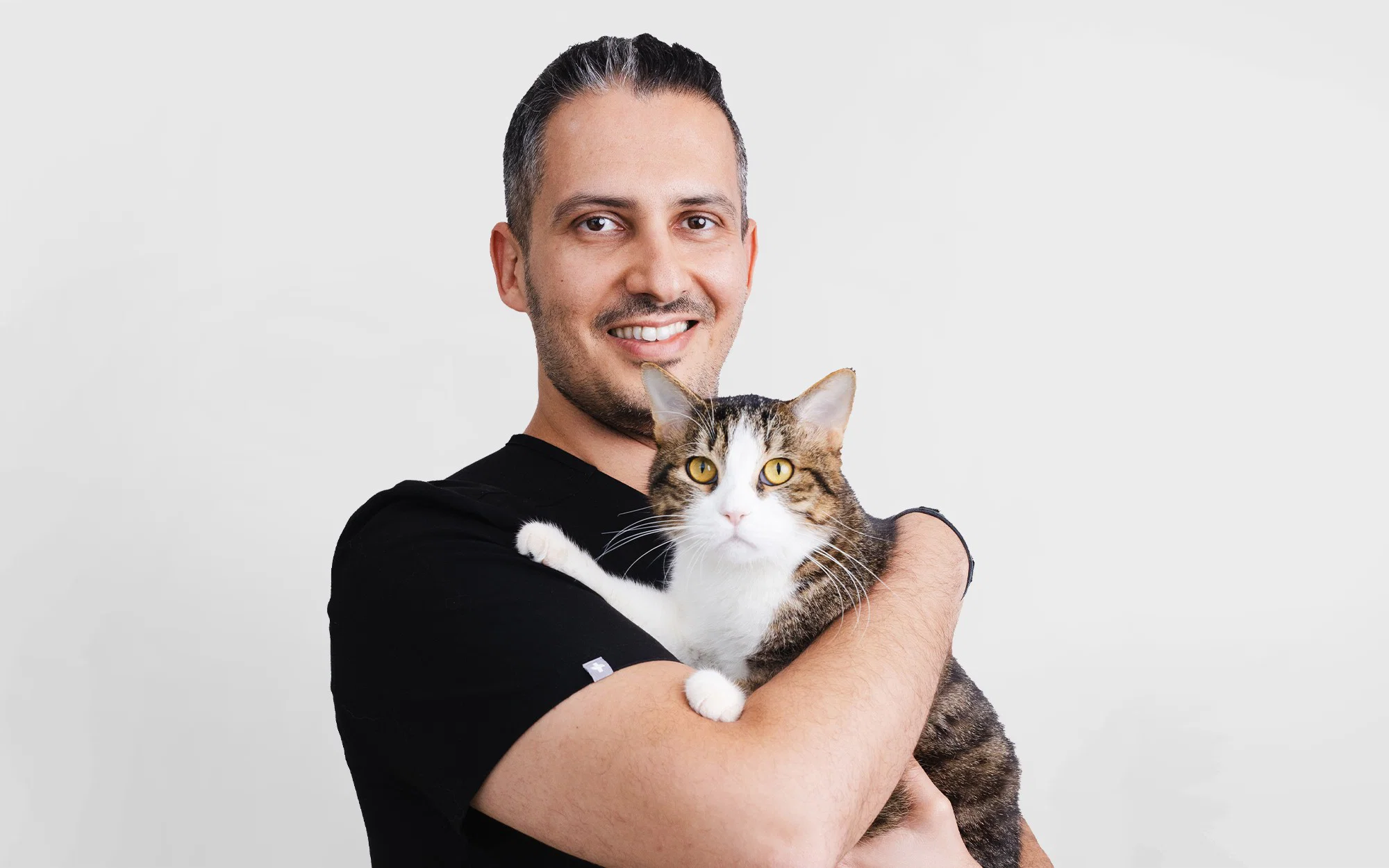 د. روكاس بروسيفيسيوس يقف مبتسمًا بجانب كلب بني صغير، مسلطًا الضوء على العلاقة الحنونة بين الطبيب البيطري وحيوانه الأليف في عيادة نوبل البيطرية.