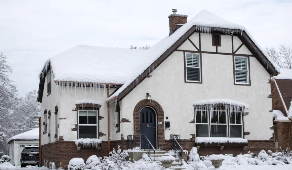 Illinois home roof damage visible from snow and ice dams along eaves after storm winter storm snowfall.