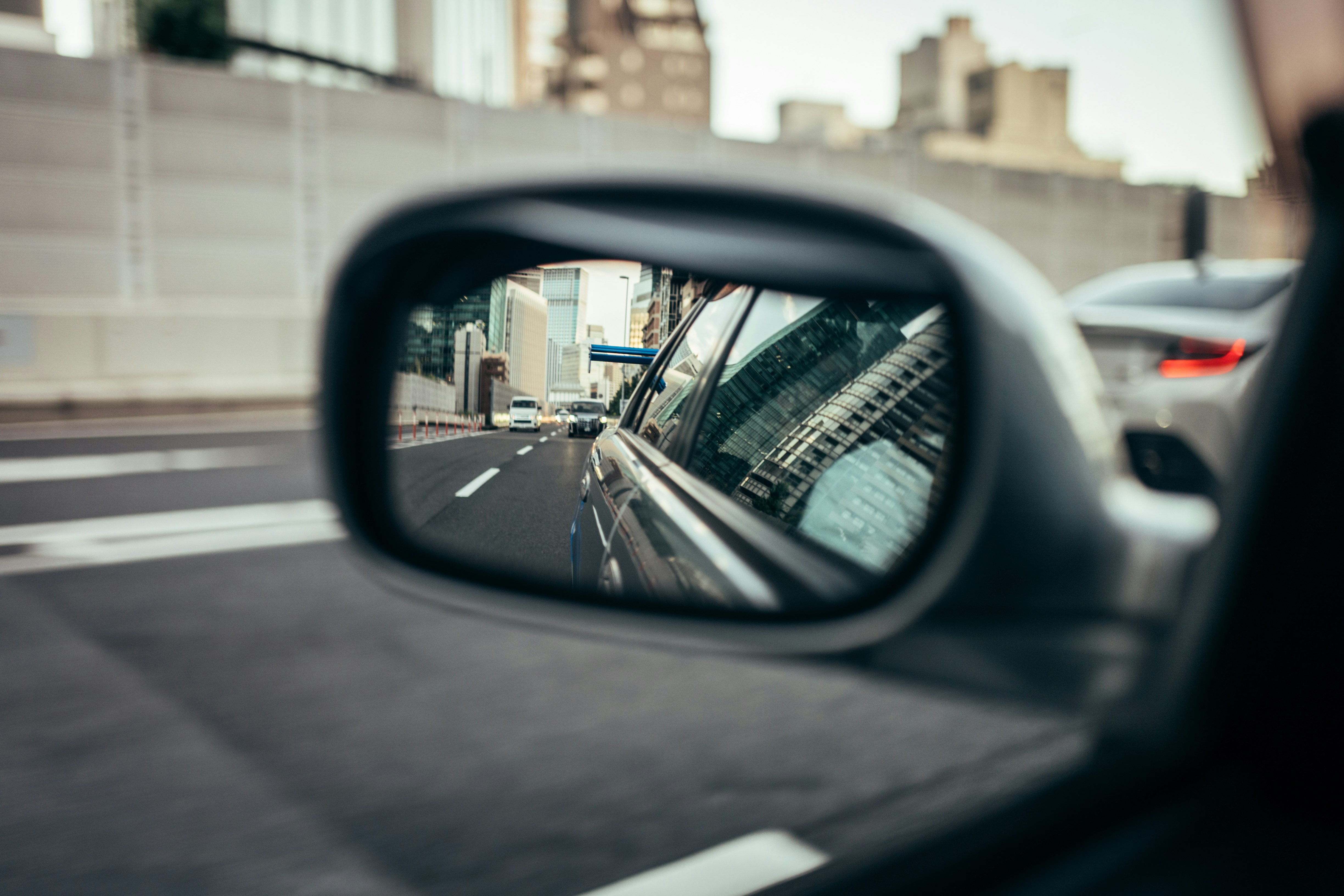 Reflection of city buildings in a car's side mirror.