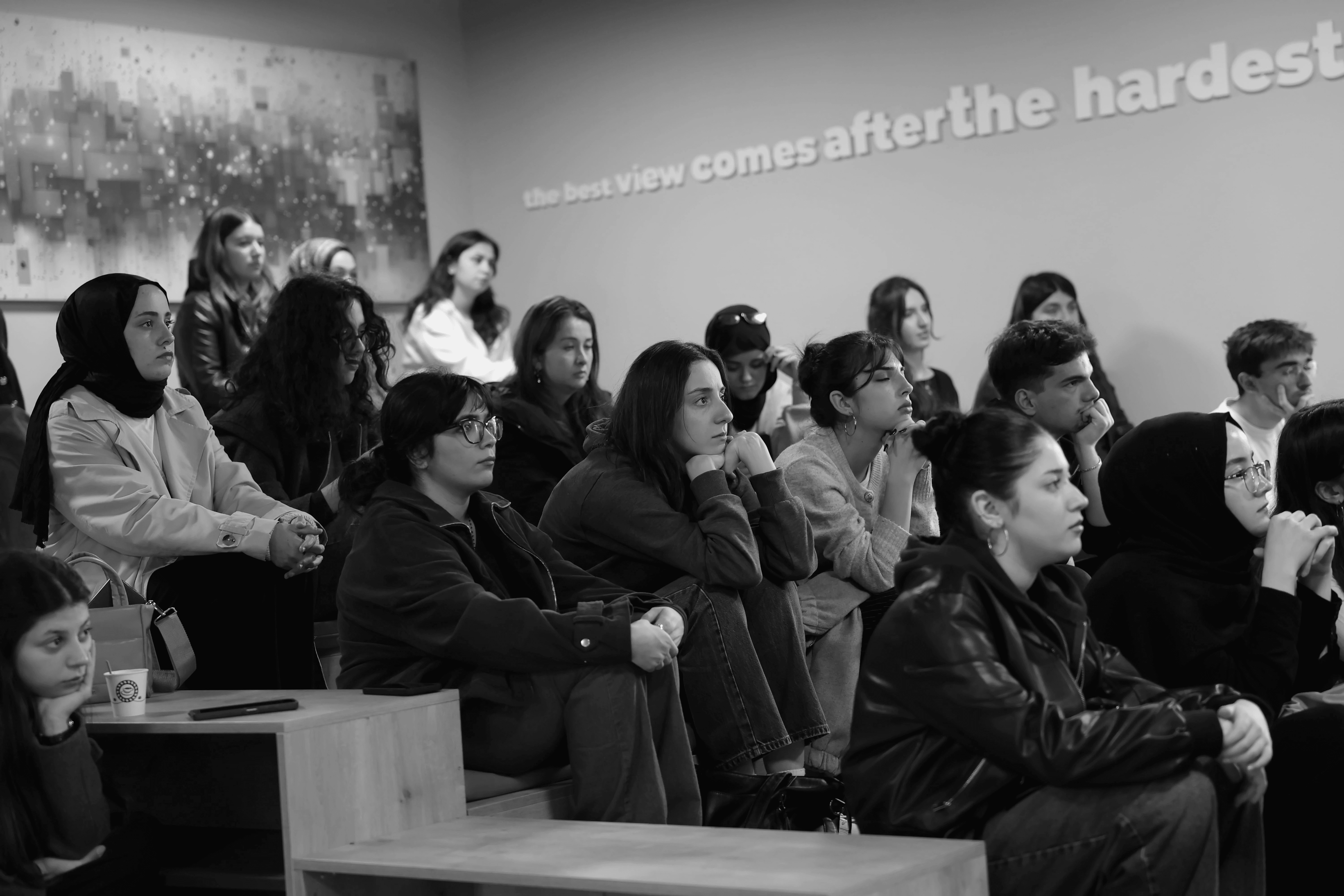 Four people engage in conversation in front of a wall with text, all smiling and interacting in a casual setting.