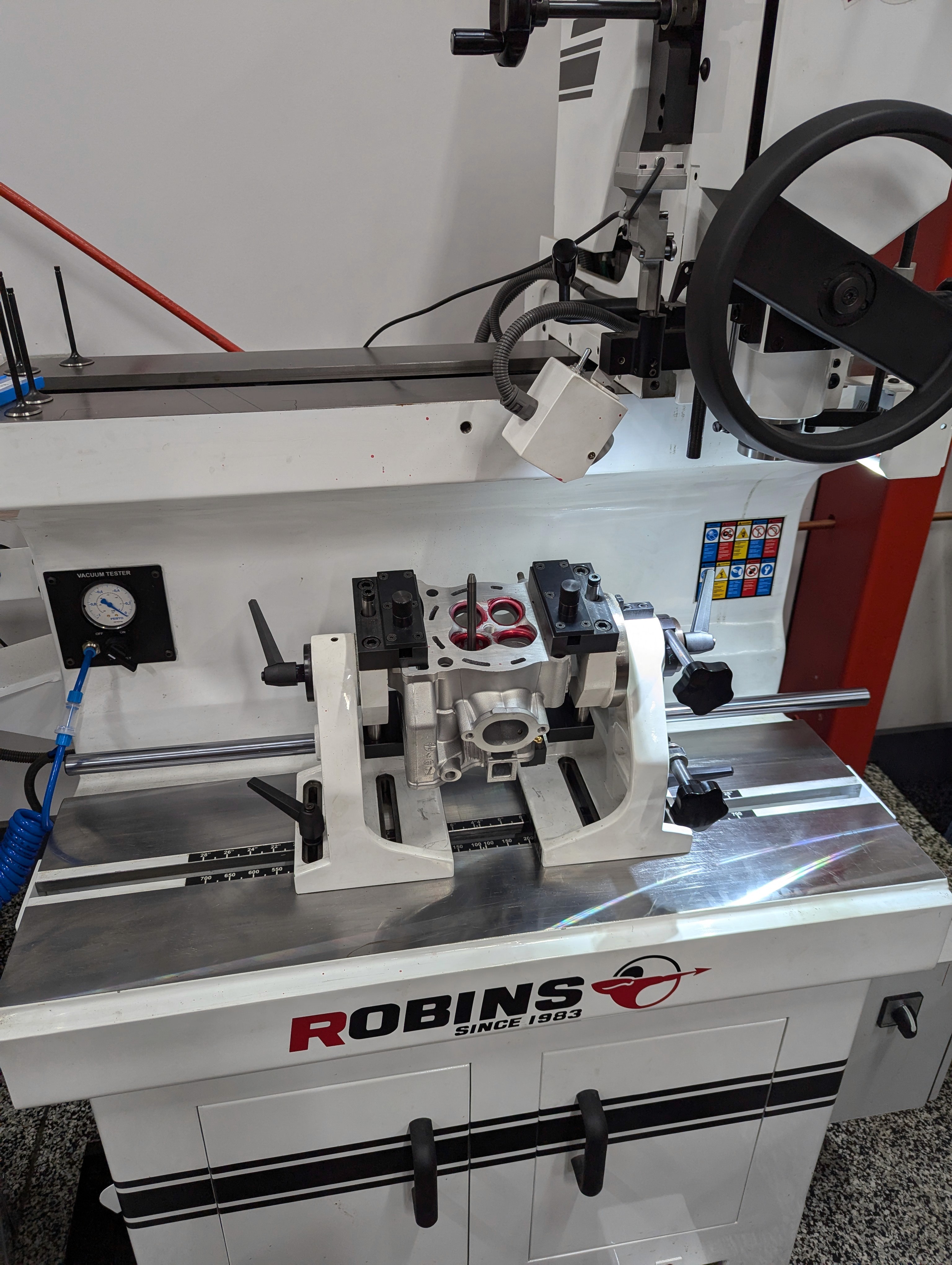 A dirt bike cylinder head mounted in a Robins valve seat machine ready to have the valve seats machined