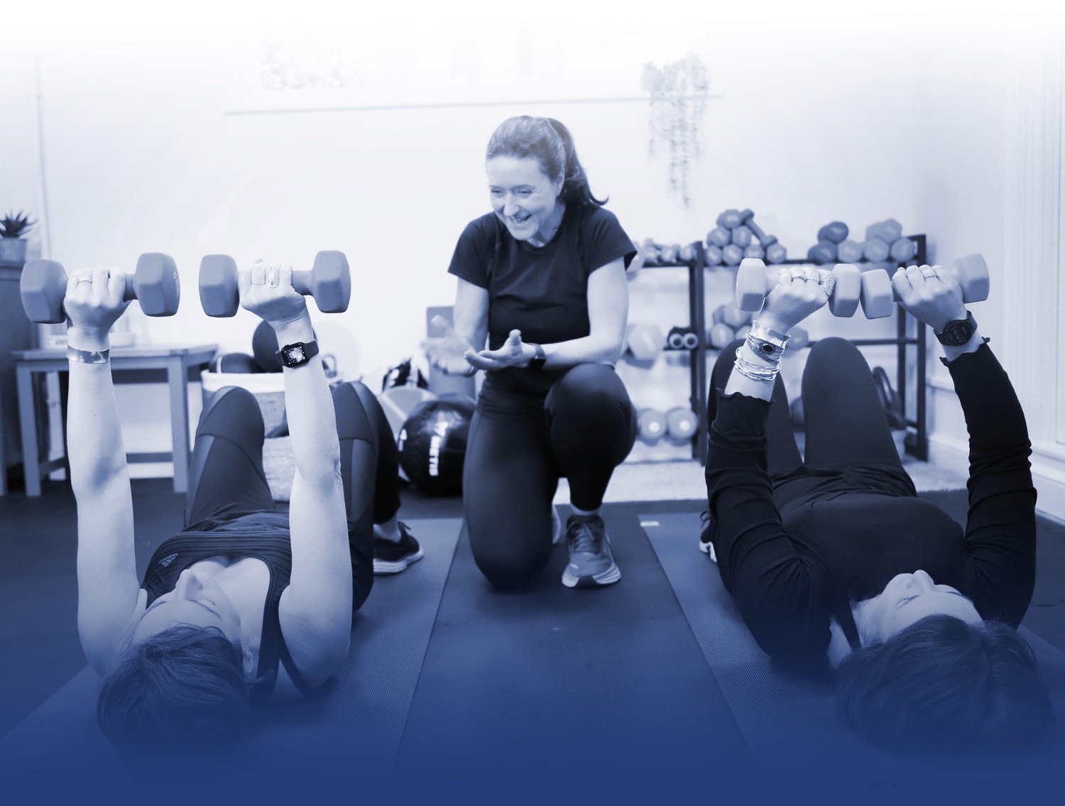 Crowborough personal trainer Sarah Marklew encouraging two clients as they lift small dumbbells in a chest press