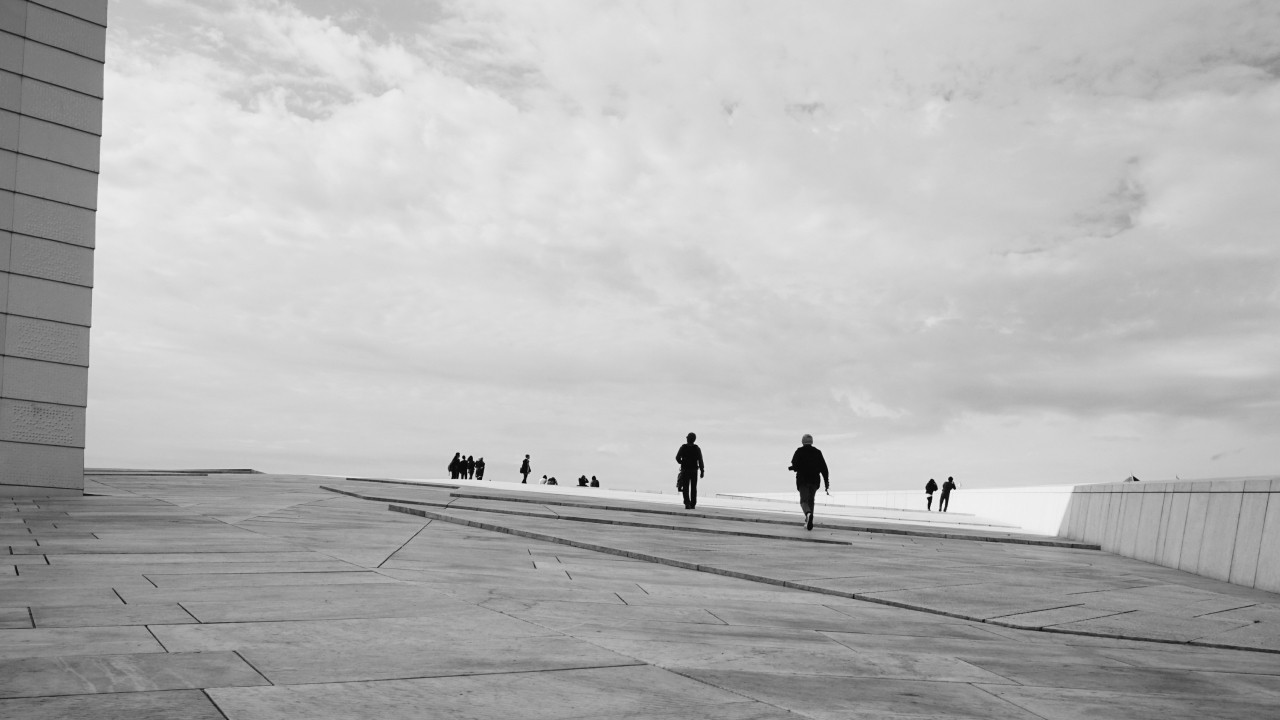 People walking across a wide paved plaza