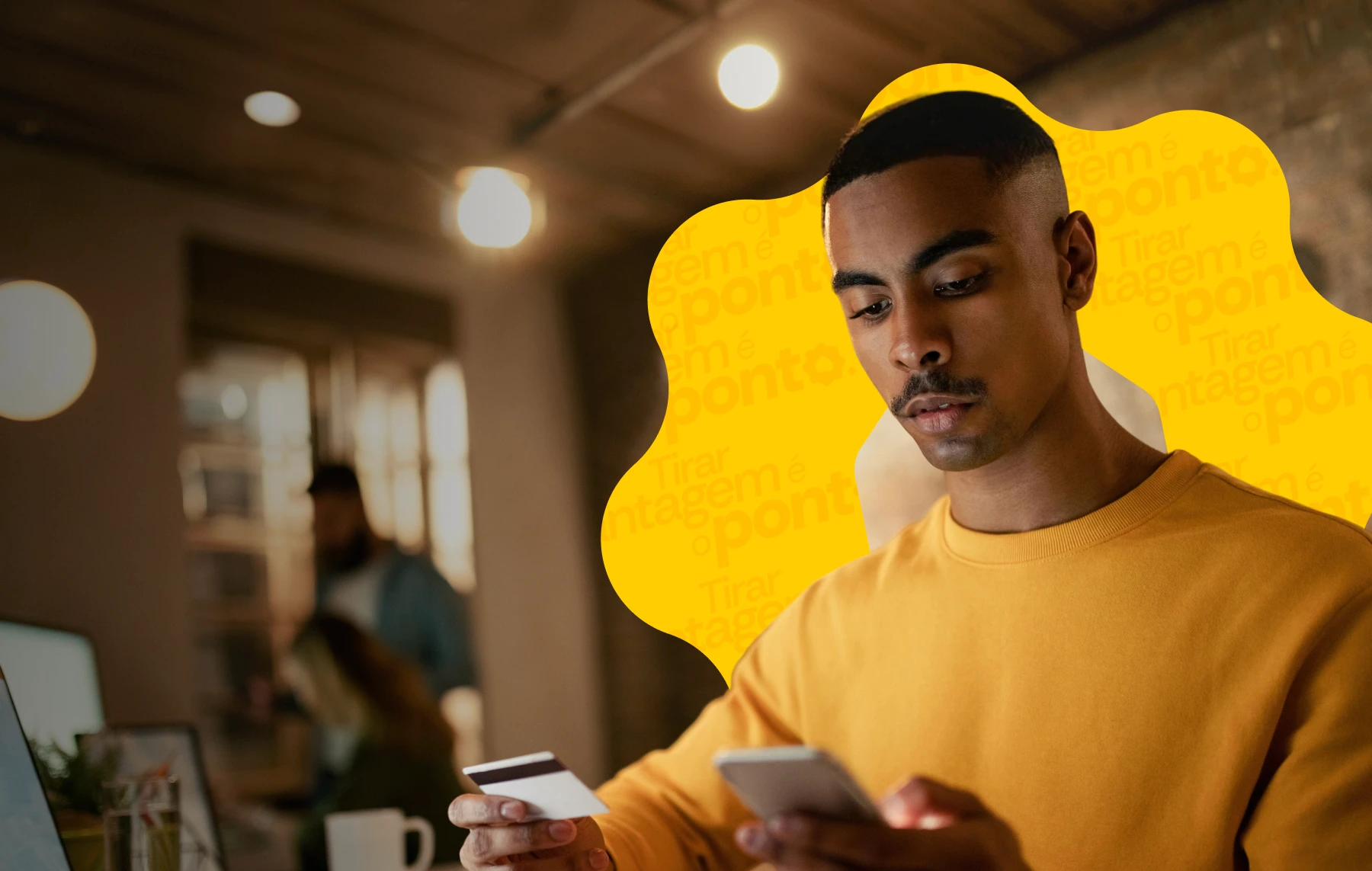 Homem jovem usando o celular e segurando um cartão de crédito