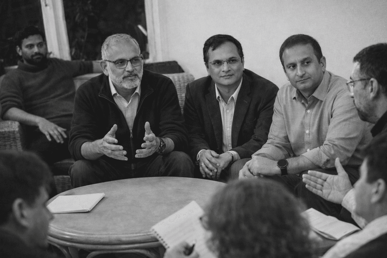 A group of six people poses on a city street, with buildings and shops visible in the background.