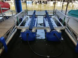 Boat lift system with two blue pontoons and metal framework, positioned between two docks, in a marina setting.