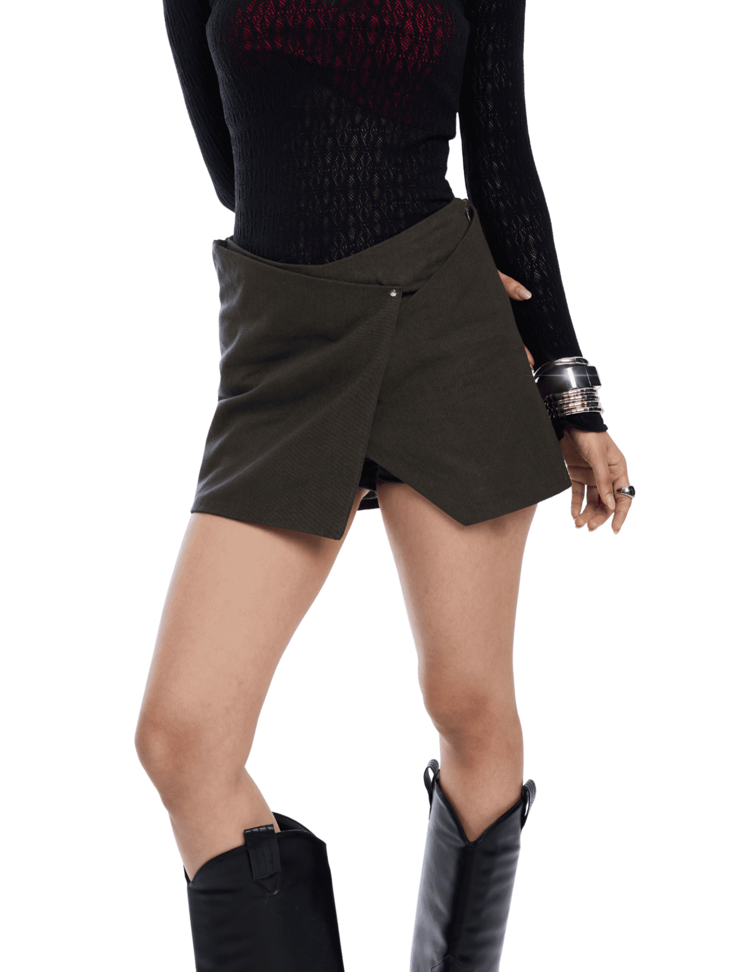 Person wearing a black top and green skirt with black boots on a white background