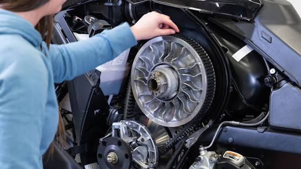 Man uses a device on a black car's bumper near exhaust pipes.