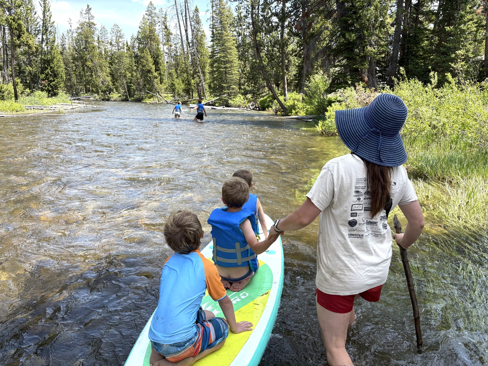 Kids wading and paddleboarding on the clear water of Alturas and Perkins Lake near Stanley, Idaho