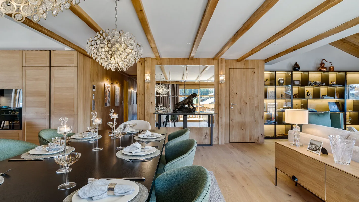 Silvretta Klosters open-space dining area with crystal chandelier, alpine timber beams, and warm backlit shelving