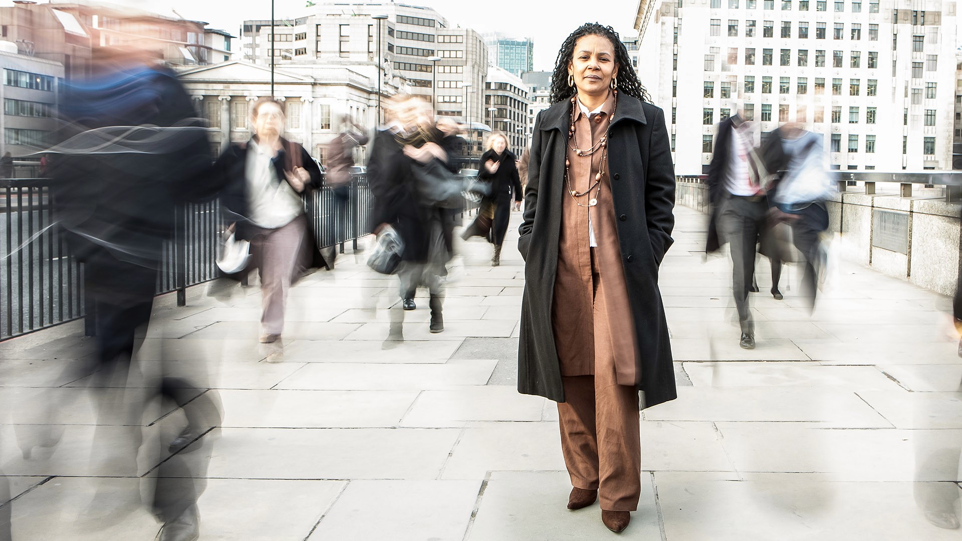 Woman standing still in busy urban sidewalk