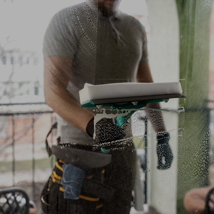 un homme très bien équipé passe un coup de raclette sur une vitre