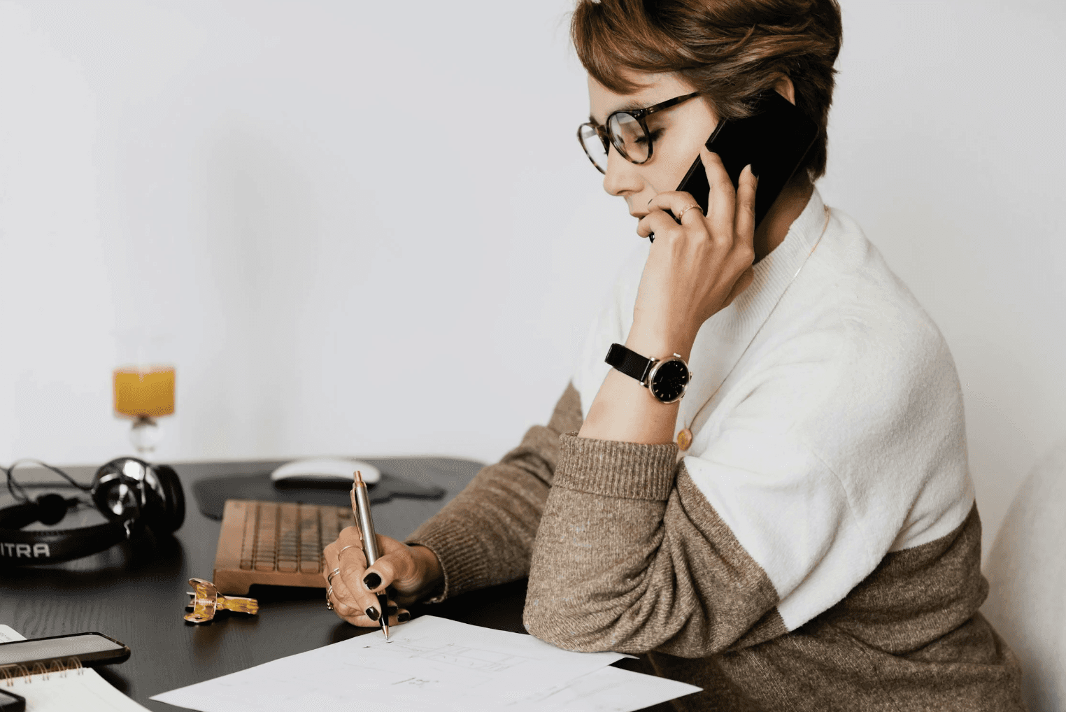 a business woman sitting on a couch with a laptop while making a call on a smart phone