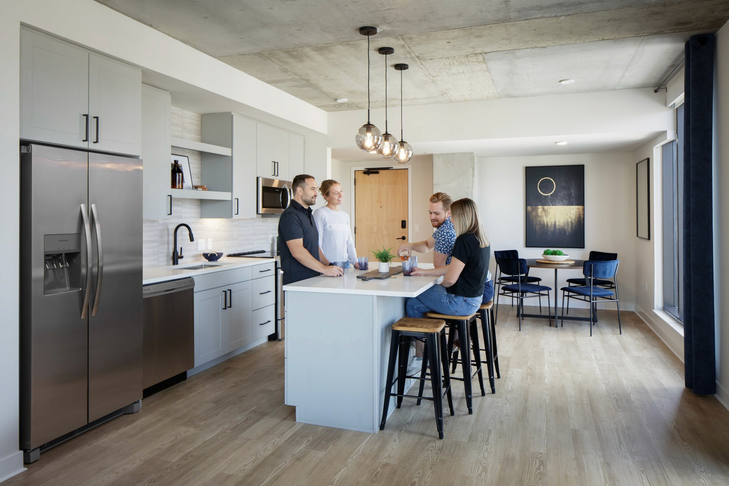 Two couples at a kitchen island in modern multifamily unit enjoying drinks