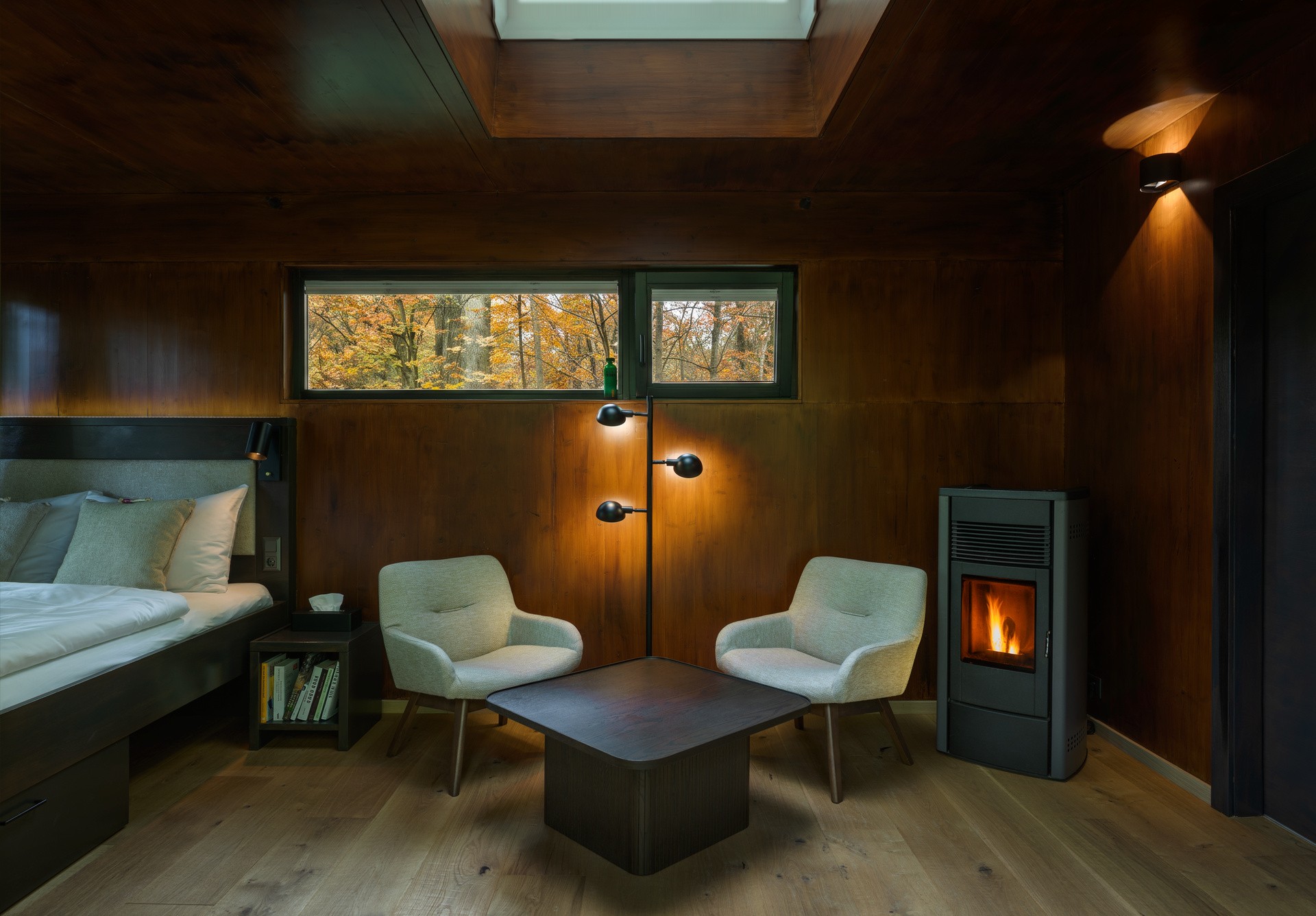 Wohnraum im Baumhaus mit Pelletsofen und Herbstwald vor dem Fenster