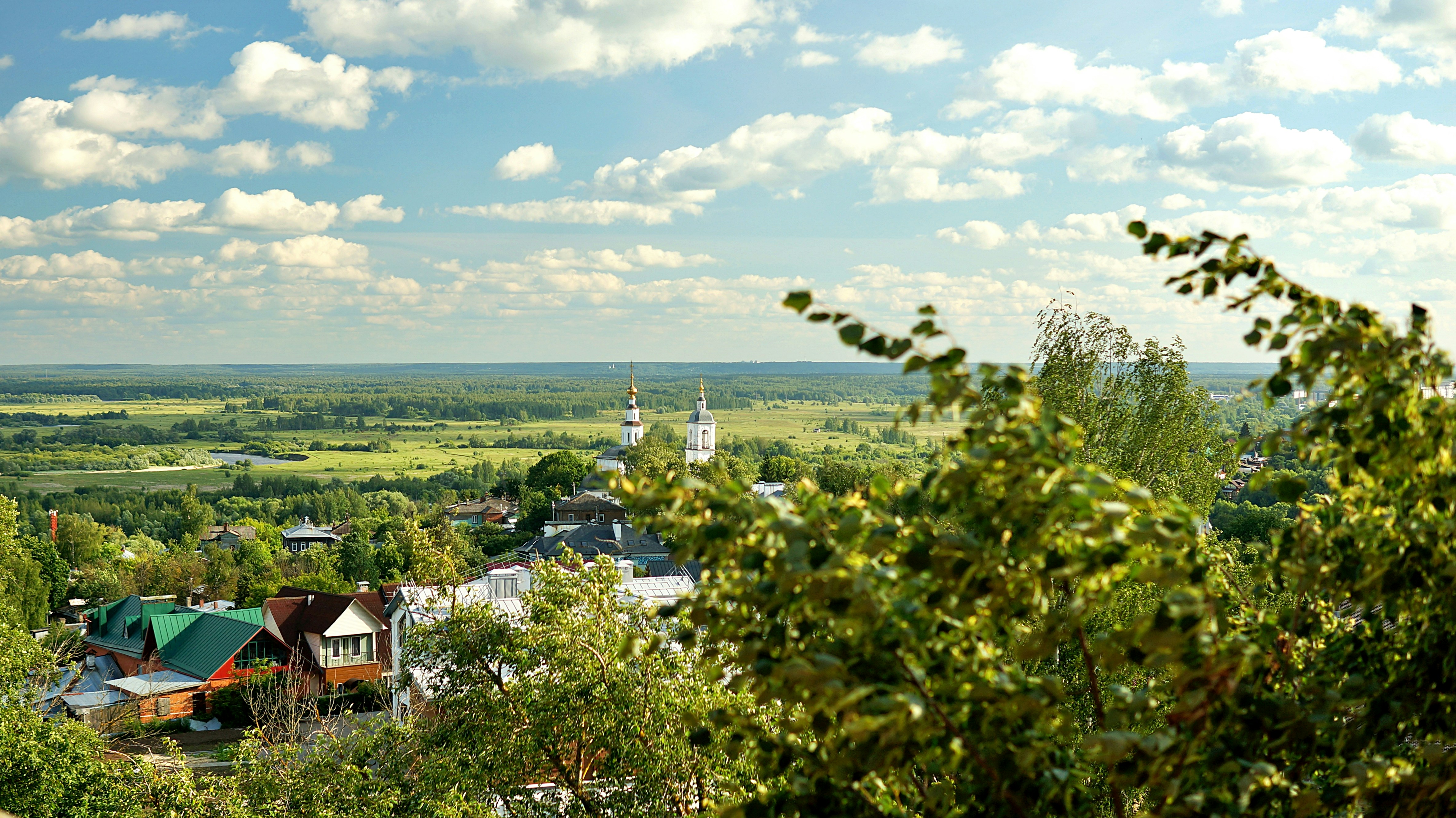 A picturesque landscape with houses, greenery, and sky.