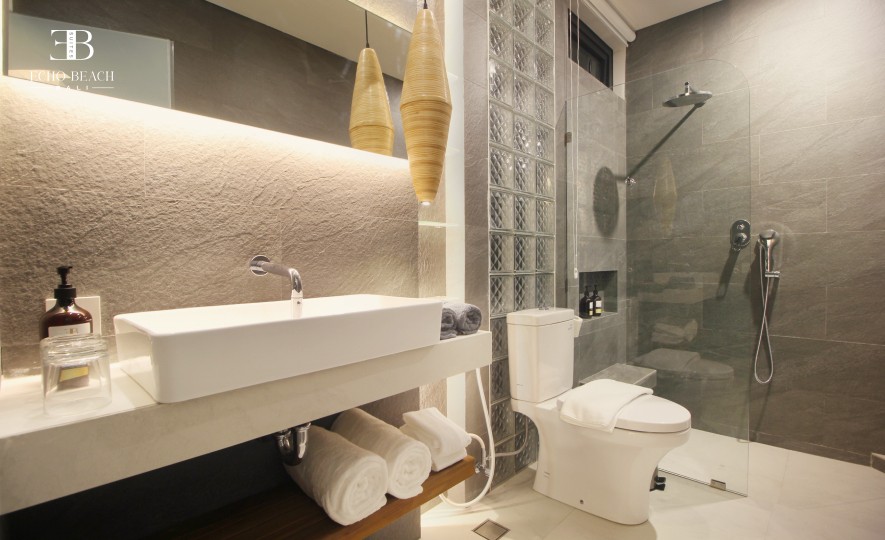 Bali Apartment Bathroom: Ensuite bathroom showing the sink, toilet, and an open wardrobe section with a visible safety box. Convenience and security at Echo Beach Suite, Canggu.