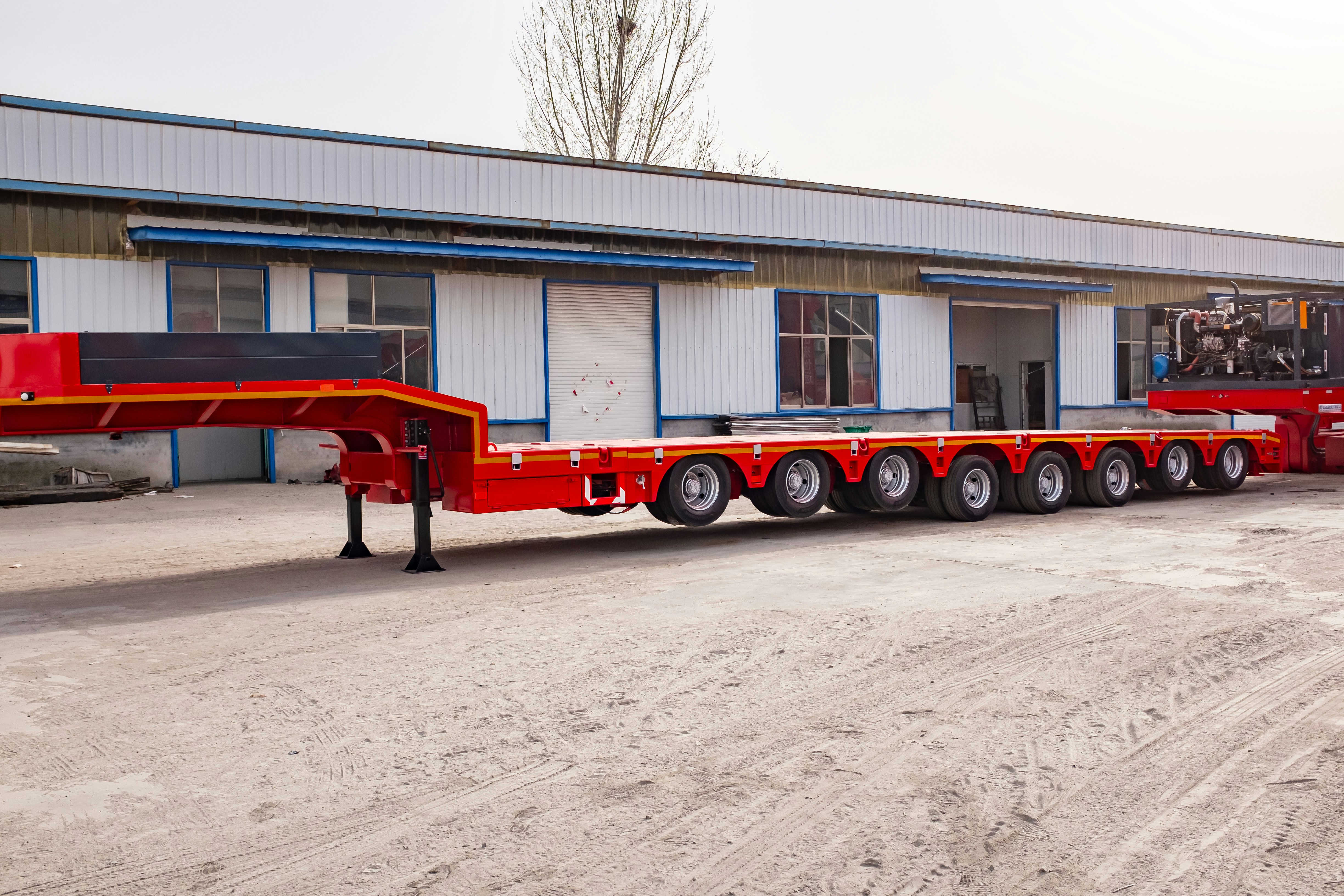 Red heavy-duty multi-axle trailer parked outside building