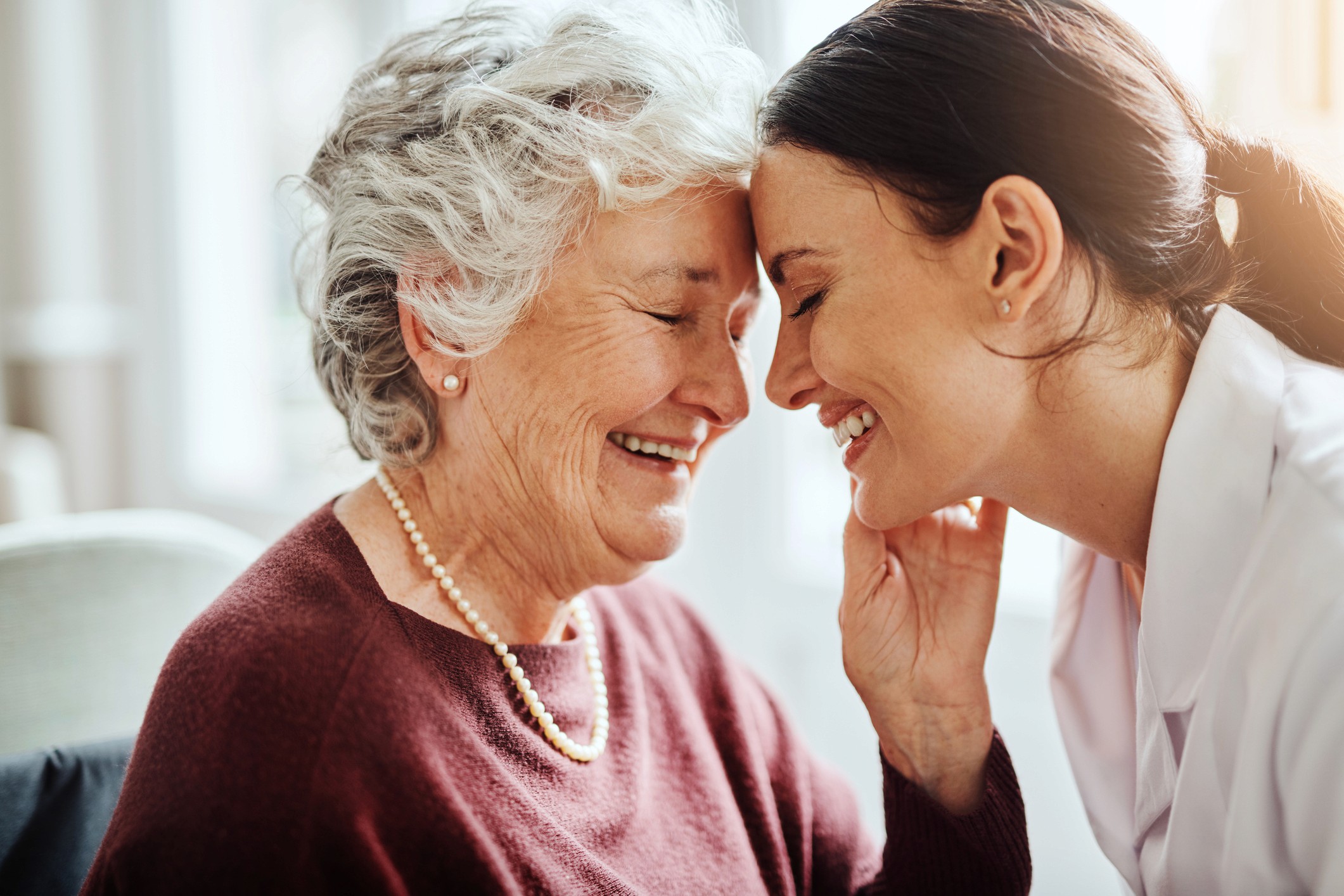 elderly patient with nurse touching heads smiling