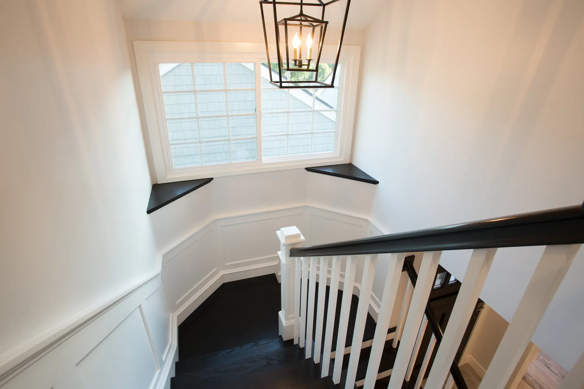 Elegant From Dana Point Cape Cod remodel, photo by Chris Darnall.black and white staircase with black handrail and white balusters.