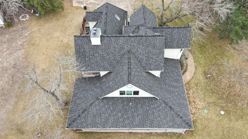 New architectural shingle roof and front porch on the Austin home, viewed by drone.