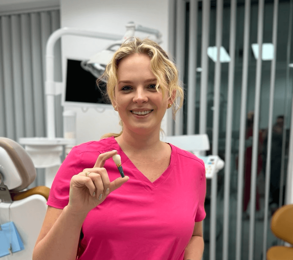 chirurg stomatolog w gabinecie dentystycznym trzymająca implant zęba z koroną