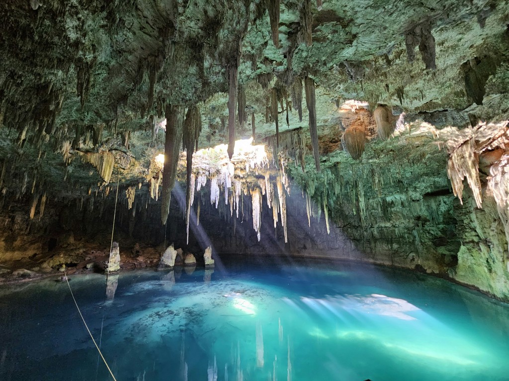 A blue pool in a cave with icicles hanging from the trees