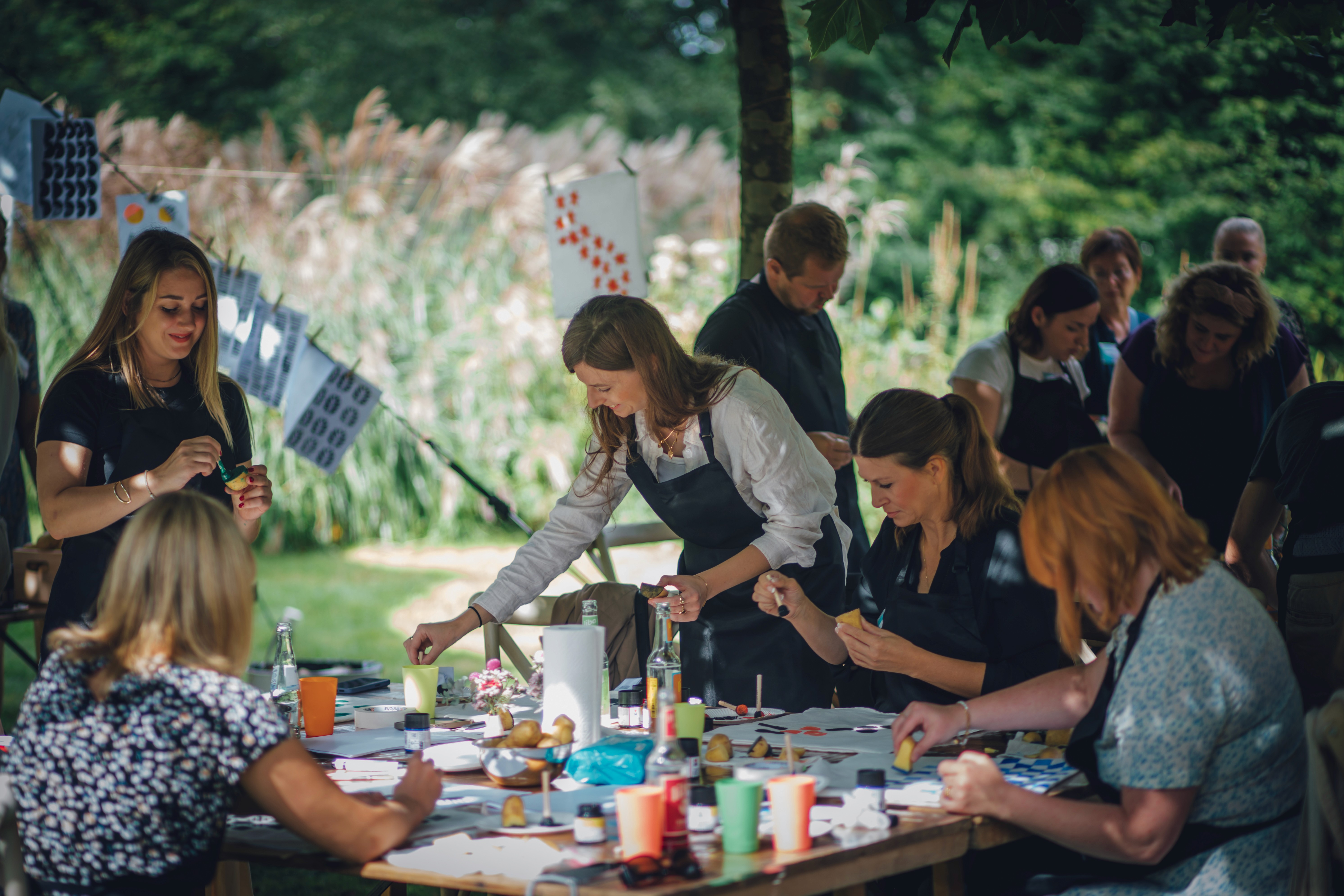 Die Creatoren gestalten gemeinsam textile Muster an einem großen Tisch bei einem Workshop von Textilwerk im Freien.