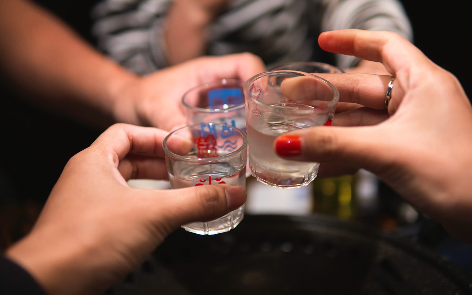 People toasting with shot glasses during Busan pub crawl.