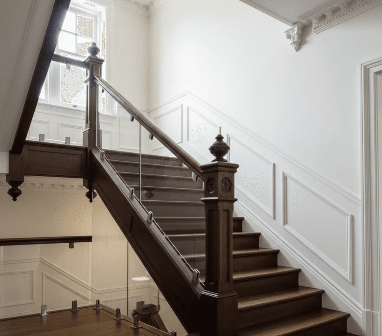 Traditional staircase updated with modern glass balustrade retrofit. 