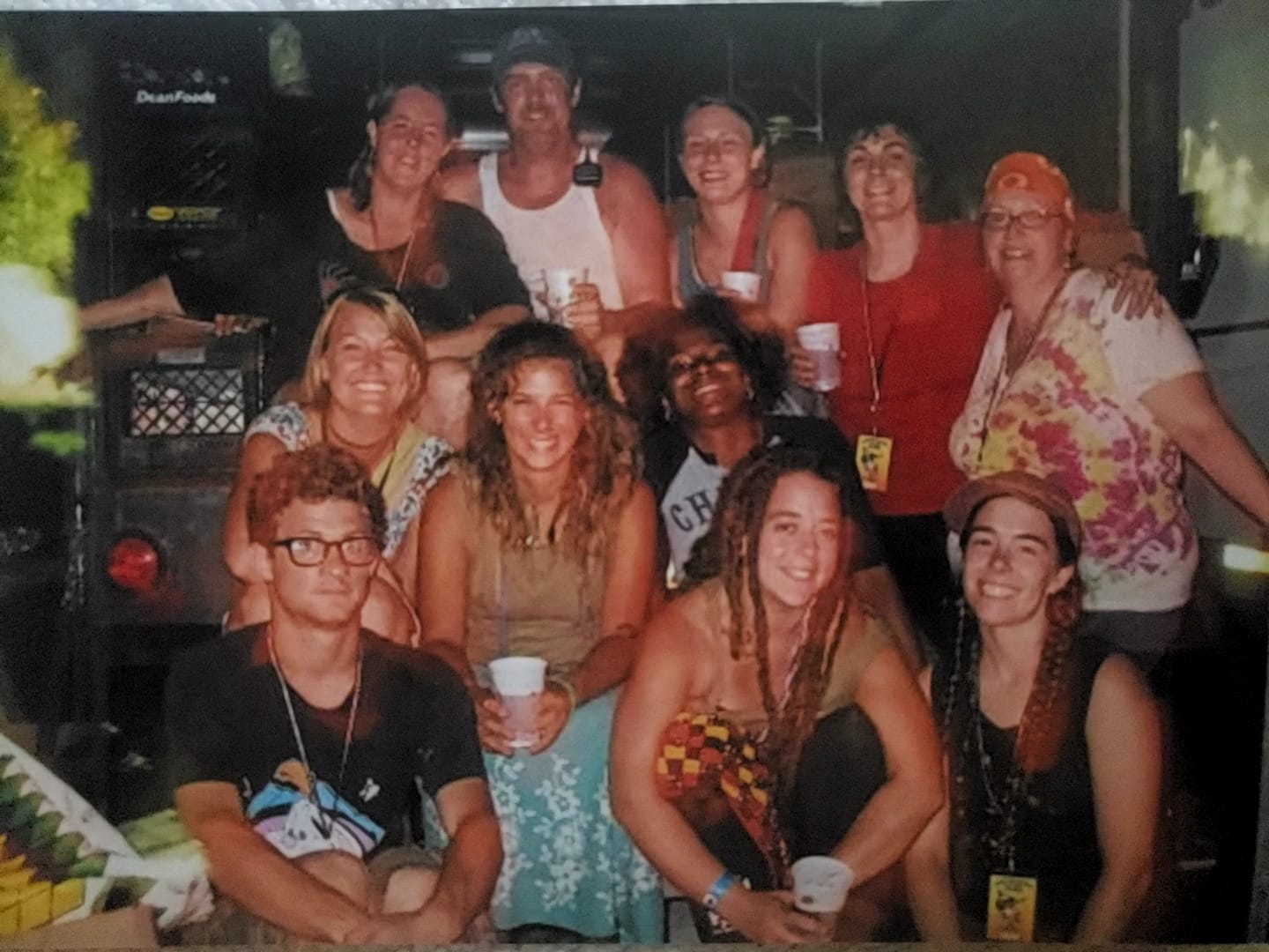 A group of twelve people working at PCS smiling and posing together in a lively indoor setting, holding drinks.