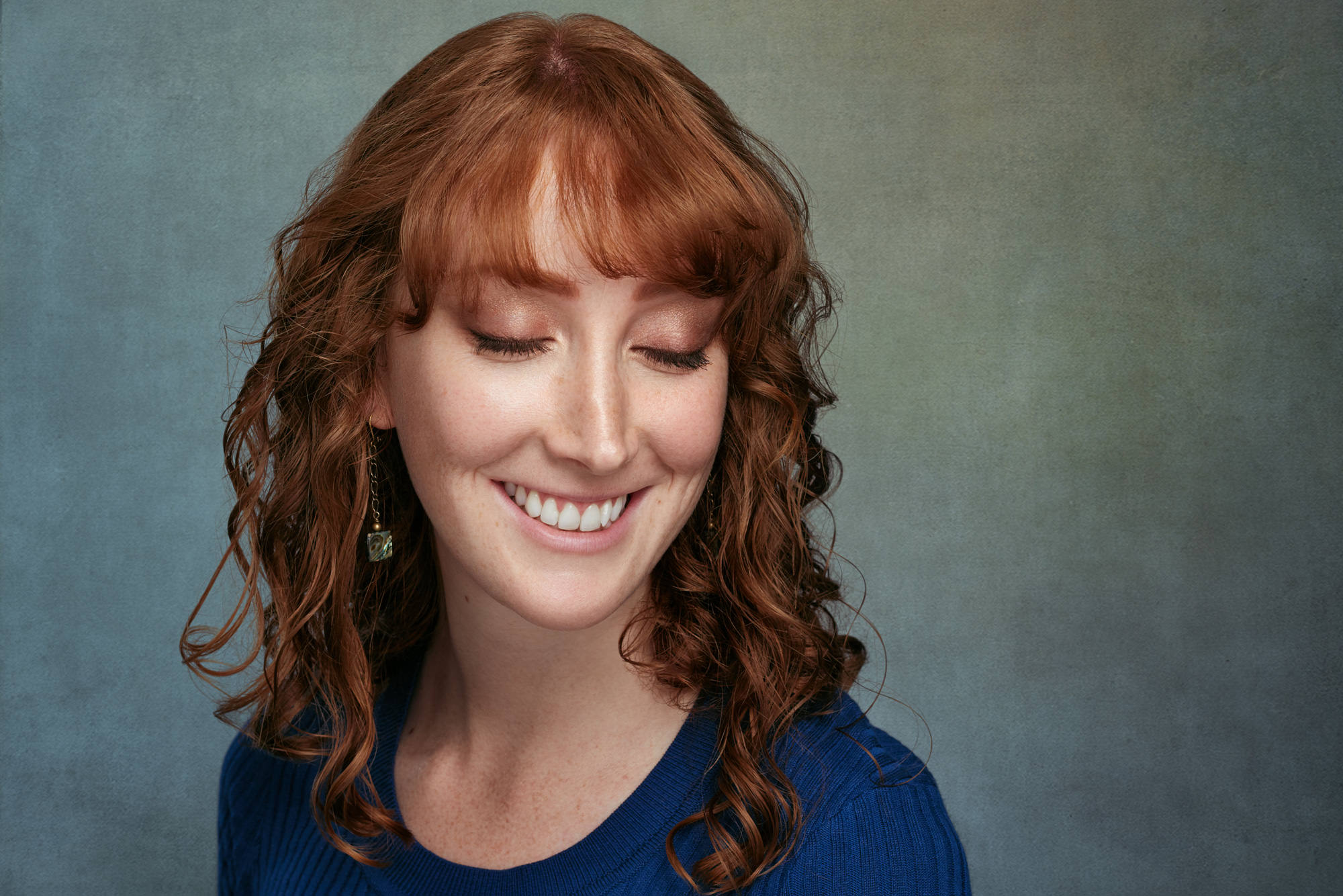 Approachable executive portrait of an asian man in a grey tee shirt blending authenticity with professional warmth. Defiant authority headshot style for non-traditional leaders.