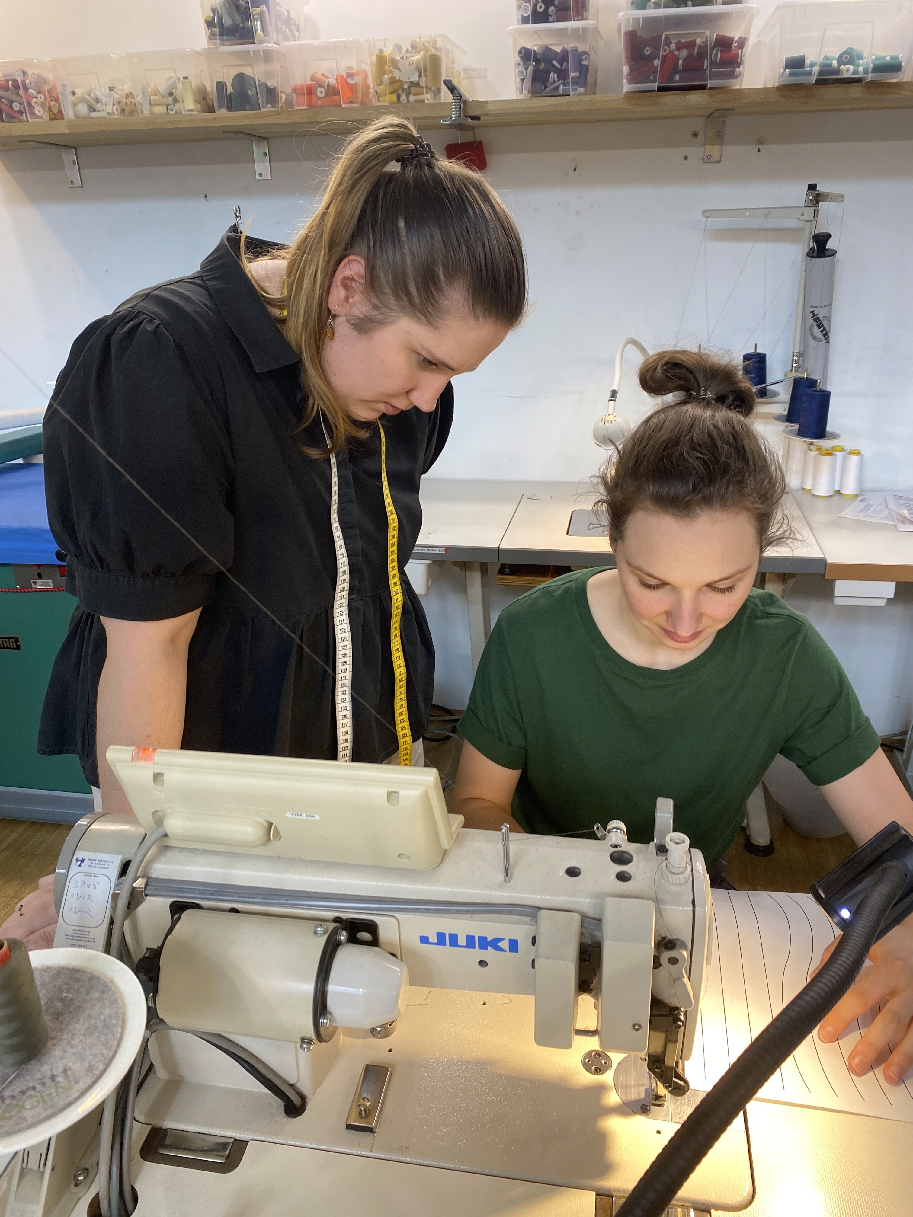 Evelin Grubbauer looking over the shoulder of a woman as she sews