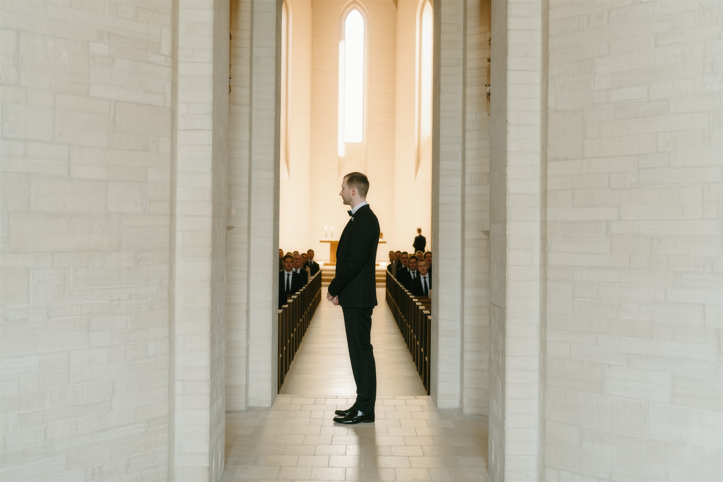 Groom standing in elegant hall with tall columns and soft natural light