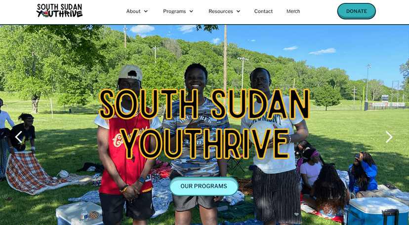 Homepage of the South Sudan Youth Thrive website, showing three youth standing in a park with bold yellow outlined text reading “SOUTH SUDAN YOUTHRIVE.”