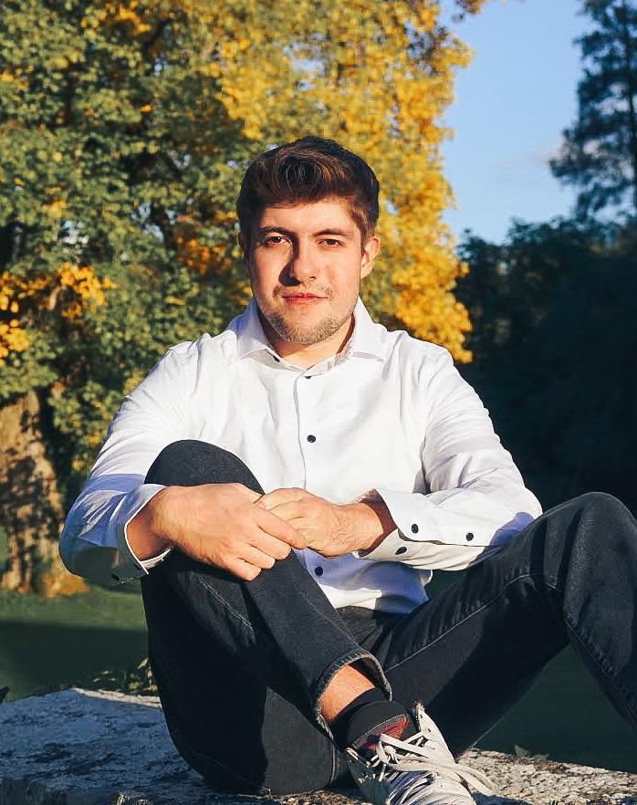 Artistic portrait of a man wearing glasses, illuminated by a diagonal streak of light against a gray background.