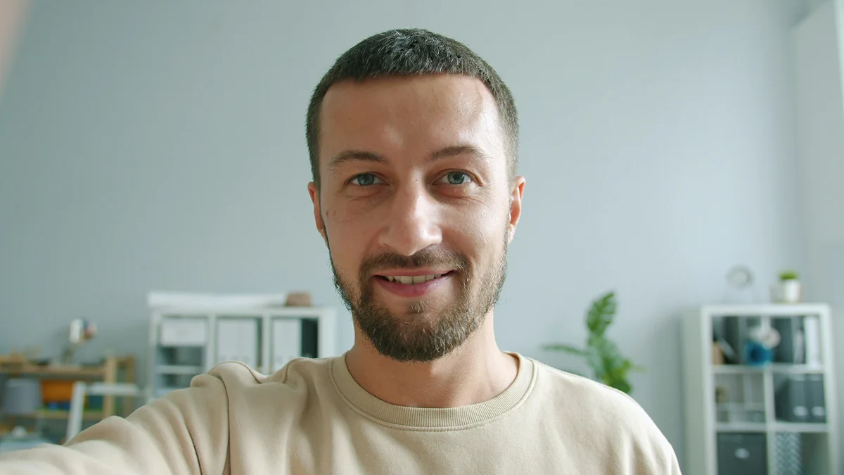 A smiling man looking toward the camera at home.