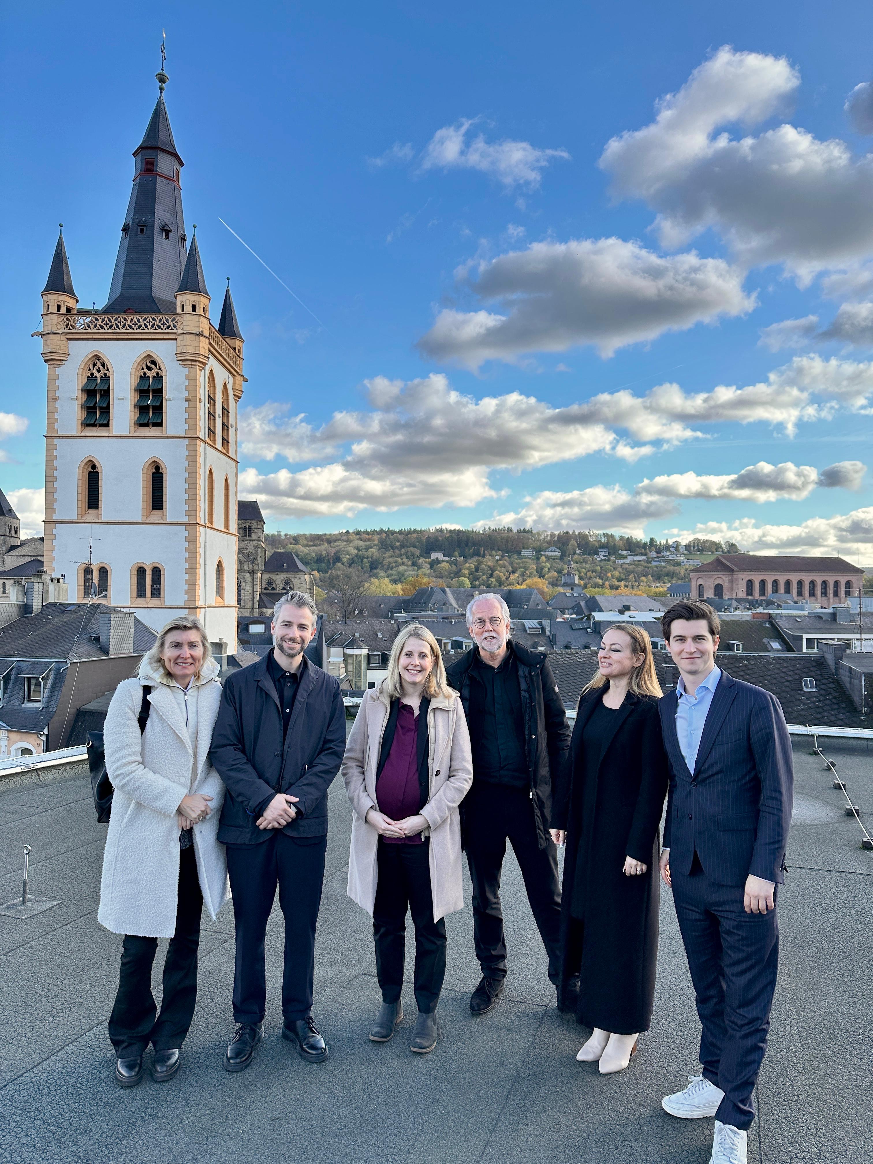 Gruppenaufnahme mehrerer Personen vor hellem Studiohintergrund mit dem Schriftzug „Meet us @ Expo Real“; Ankündigung eines Messebesuchs von MAAS & PARTNER.