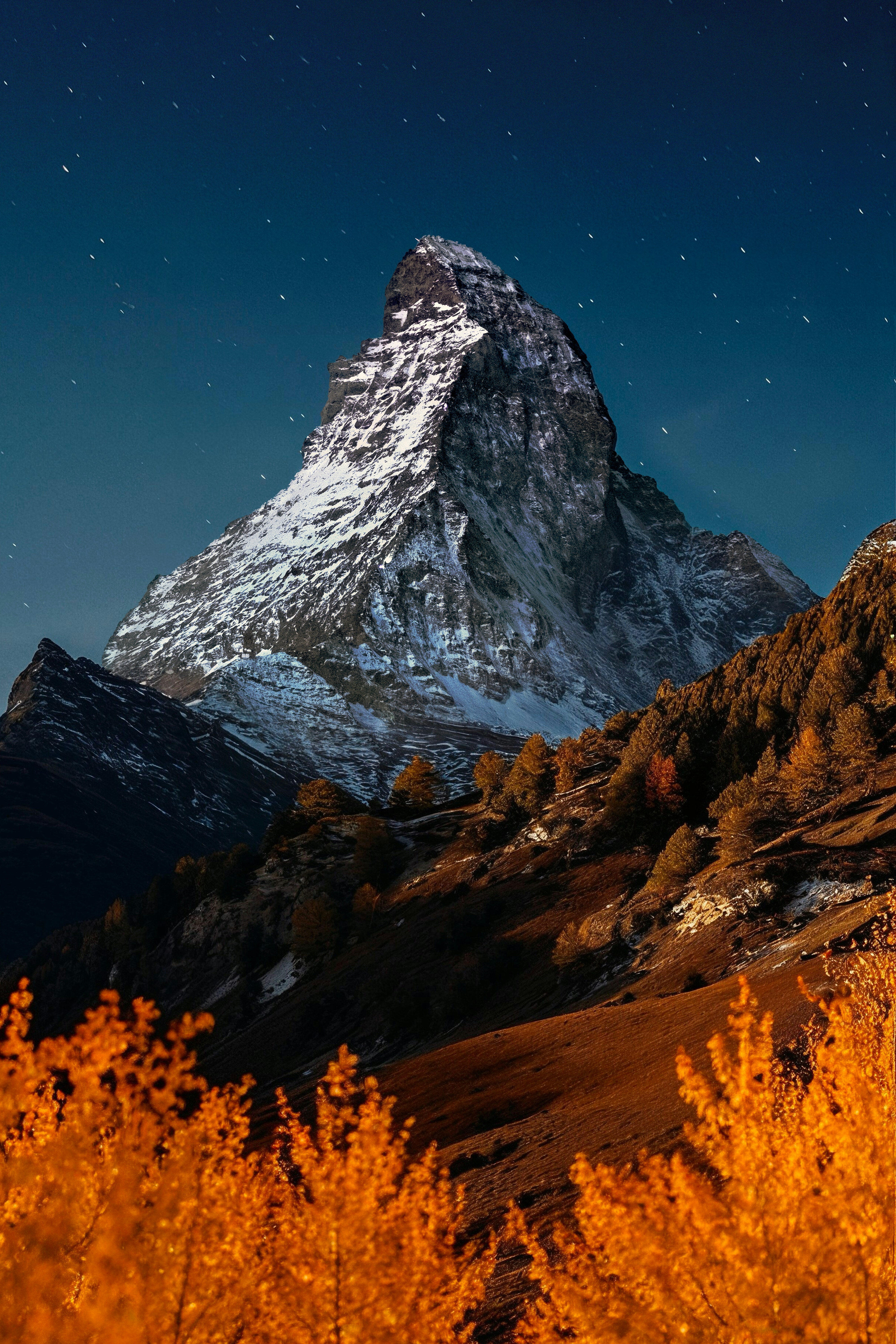 Snow-capped mountain peak under a starry night sky.