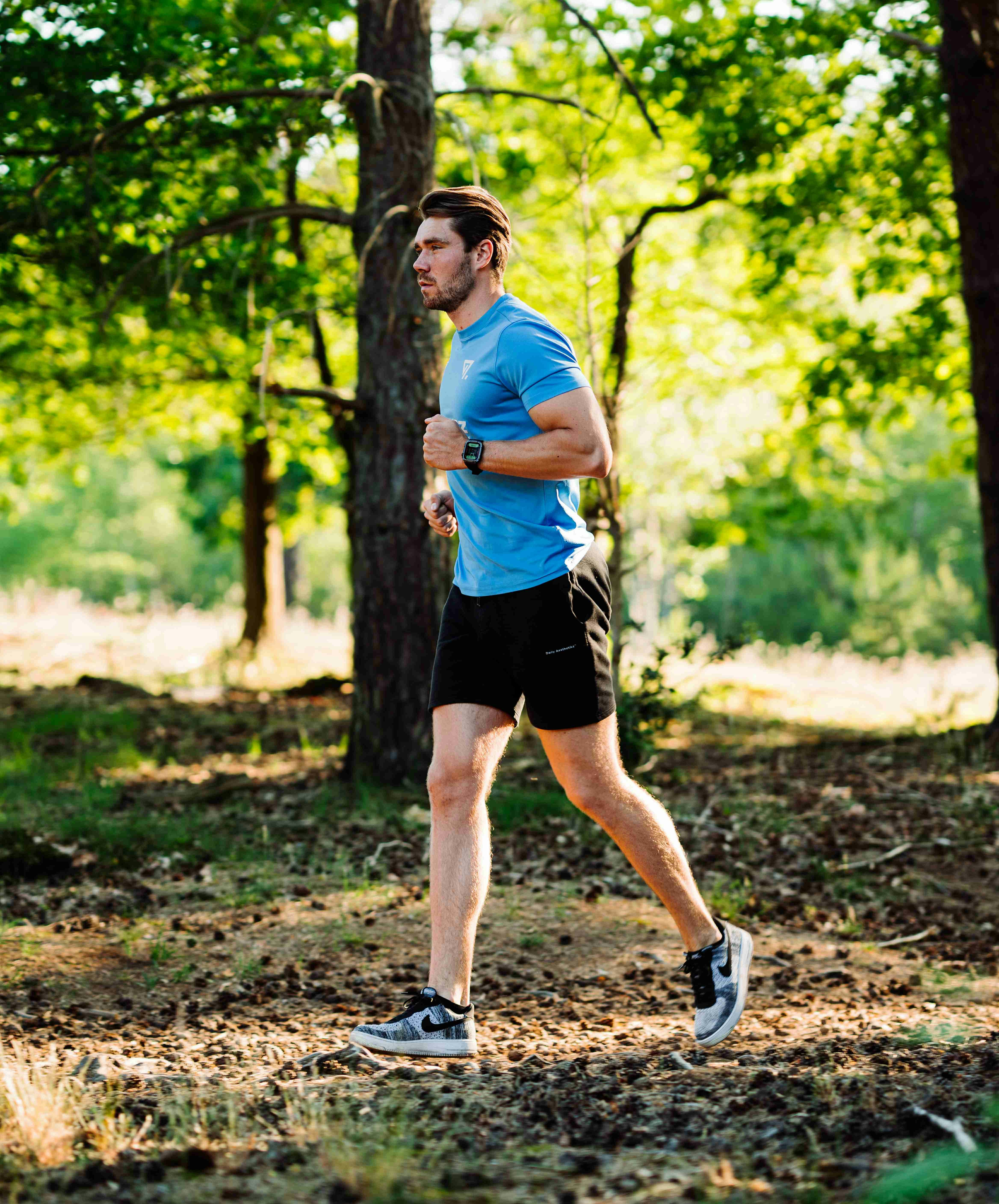 A man running through the woods in a blue shirt