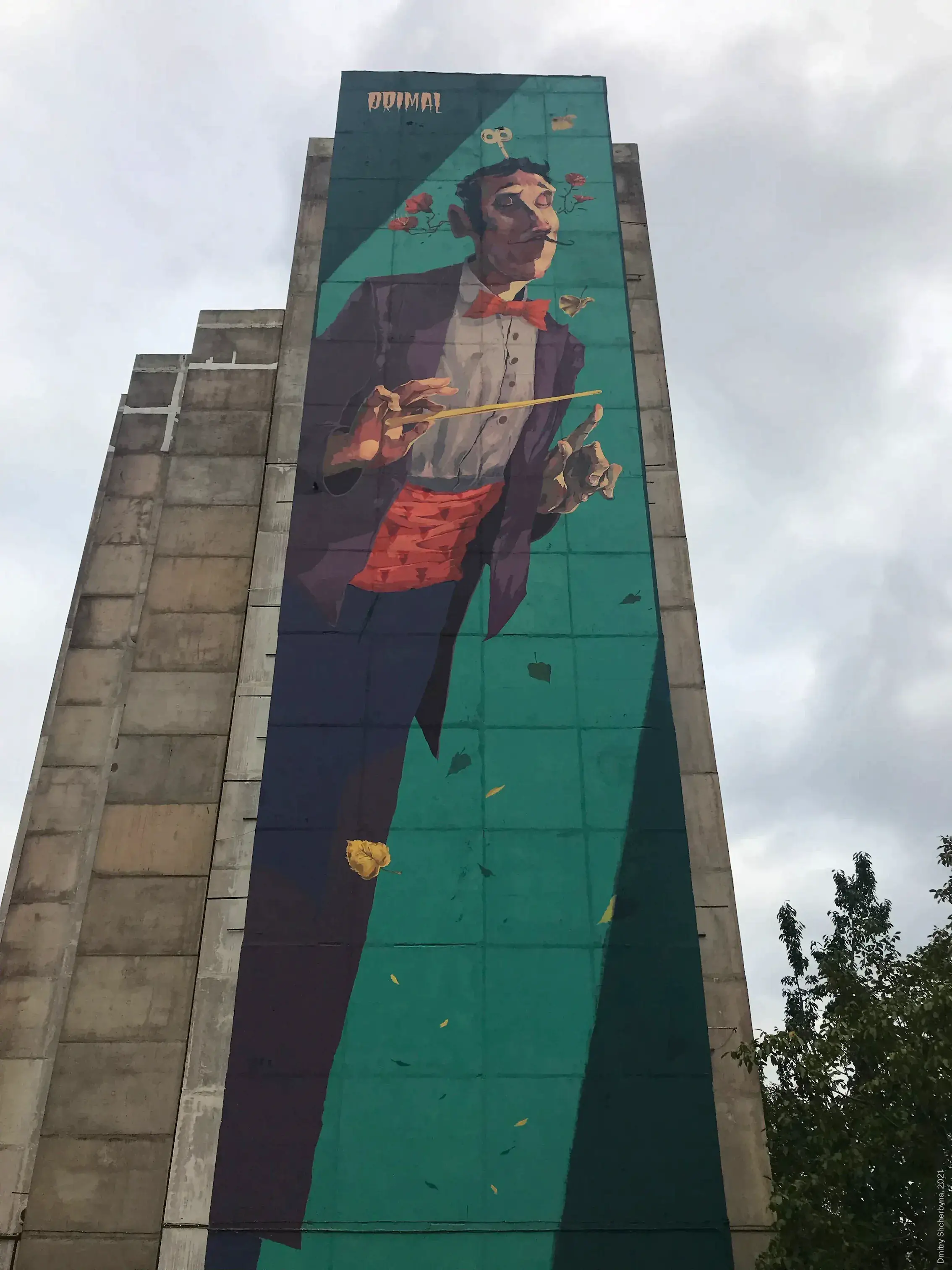 Large-scale mural on a concrete tower depicting a dapper orchestra conductor in a purple tuxedo with a red bow tie and cummerbund, holding a baton while roses and autumn leaves swirl around him against a teal background.