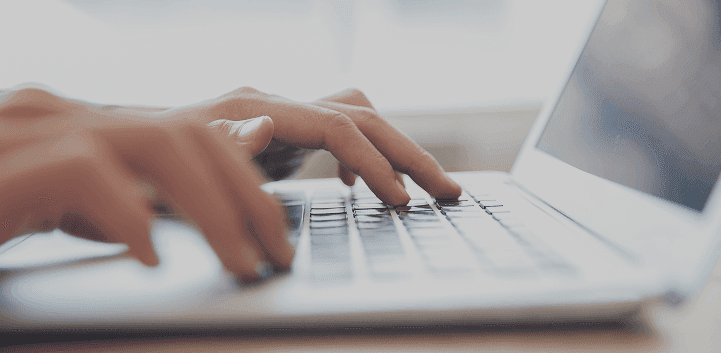 Profissional trabalhando em frente a dois monitores com código na tela.