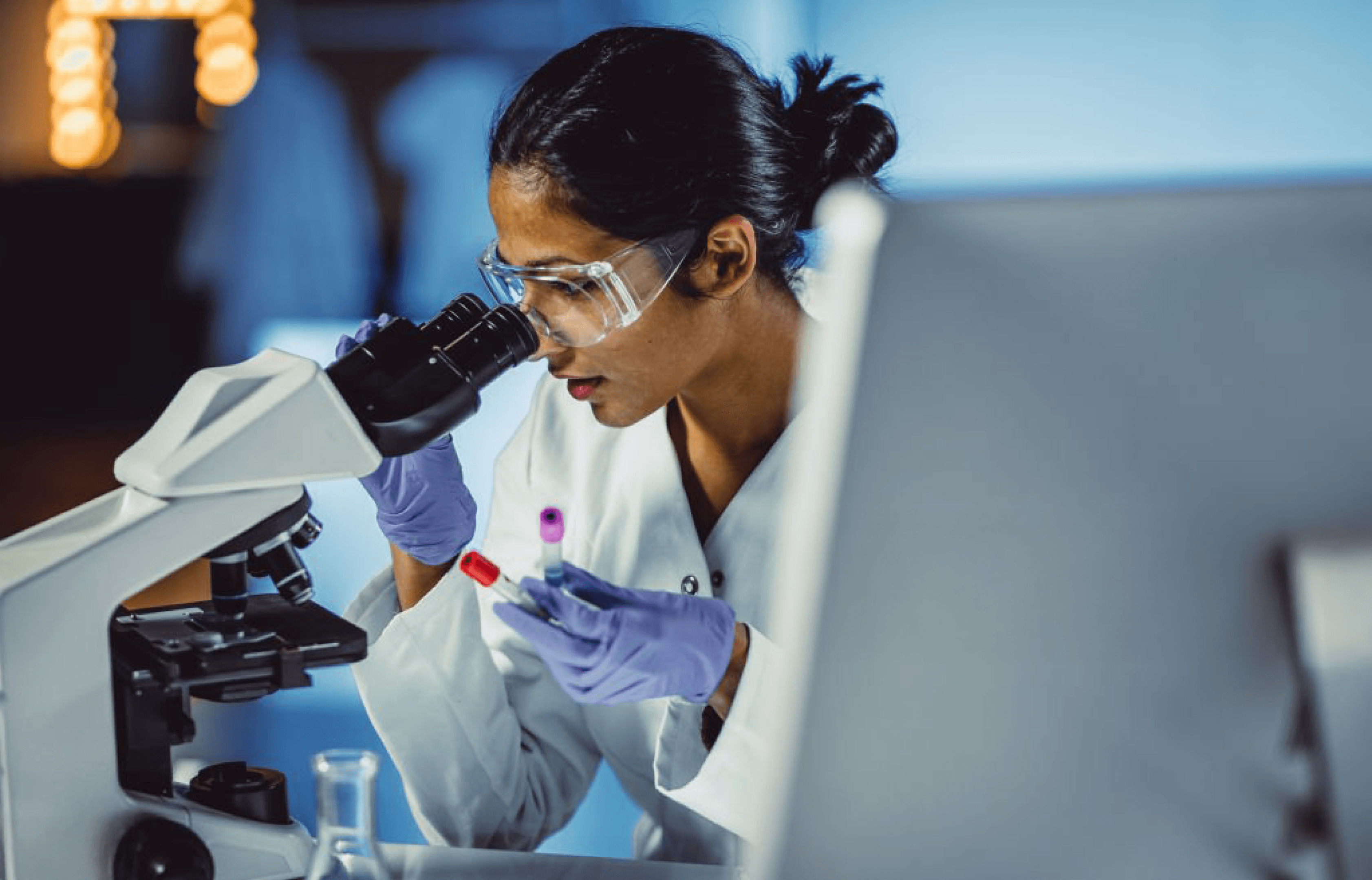 Female scientist examining samples through a microscope in a laboratory, promoting women in science and research.