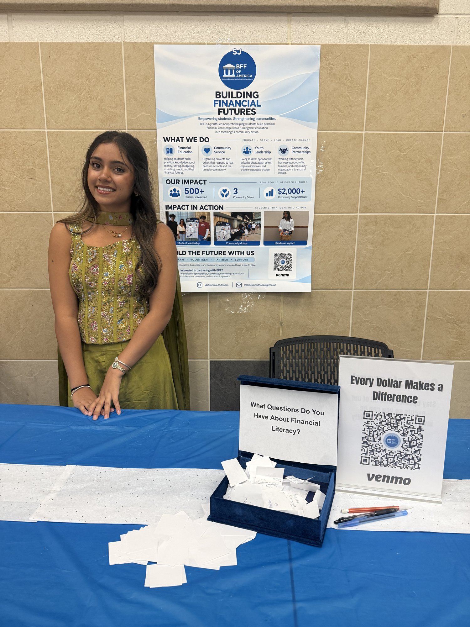 A BFF volunteer stands at an outreach table with a BFF poster and question box.