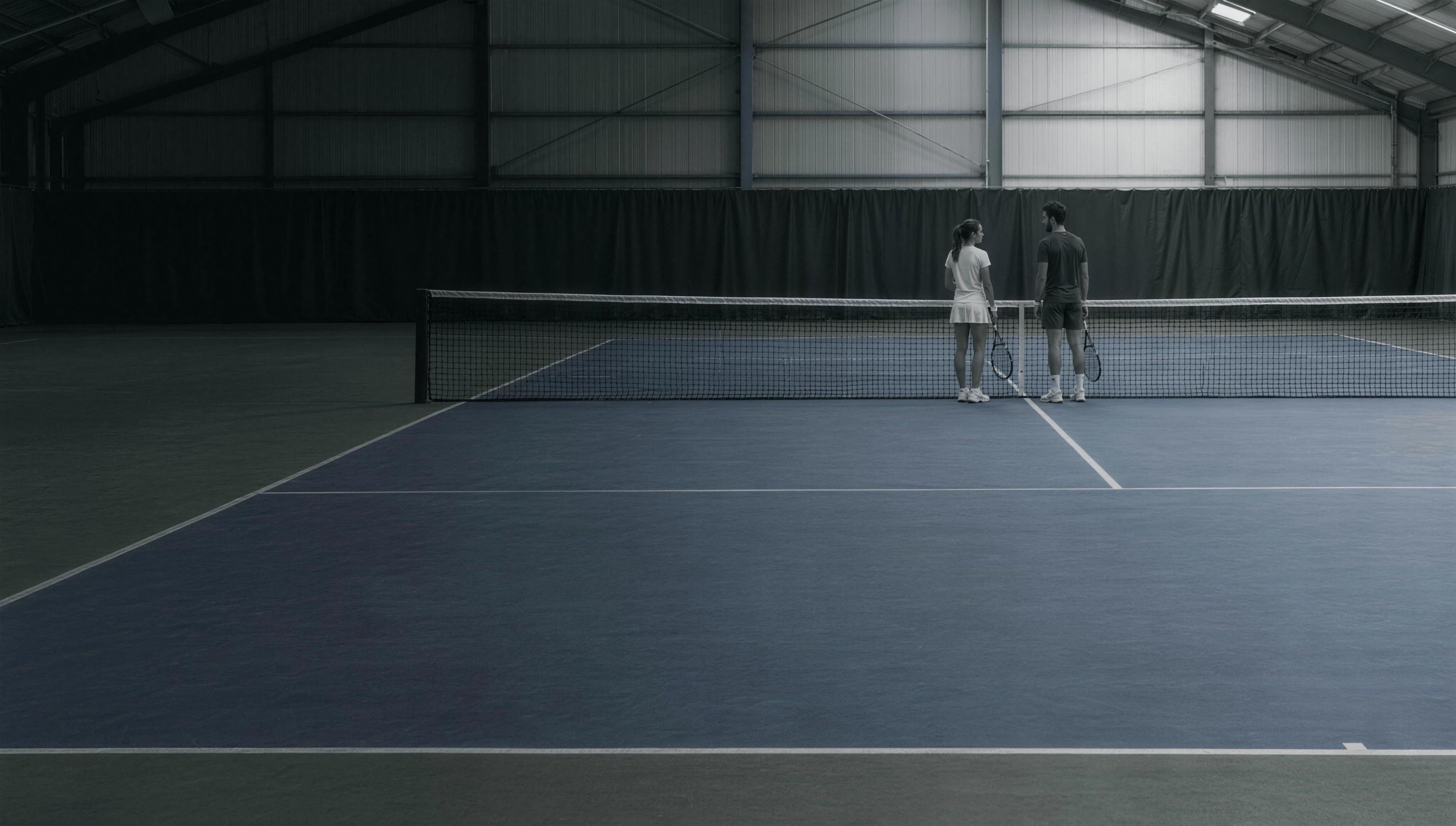 Two tennis players talking at the net on the indoor courts