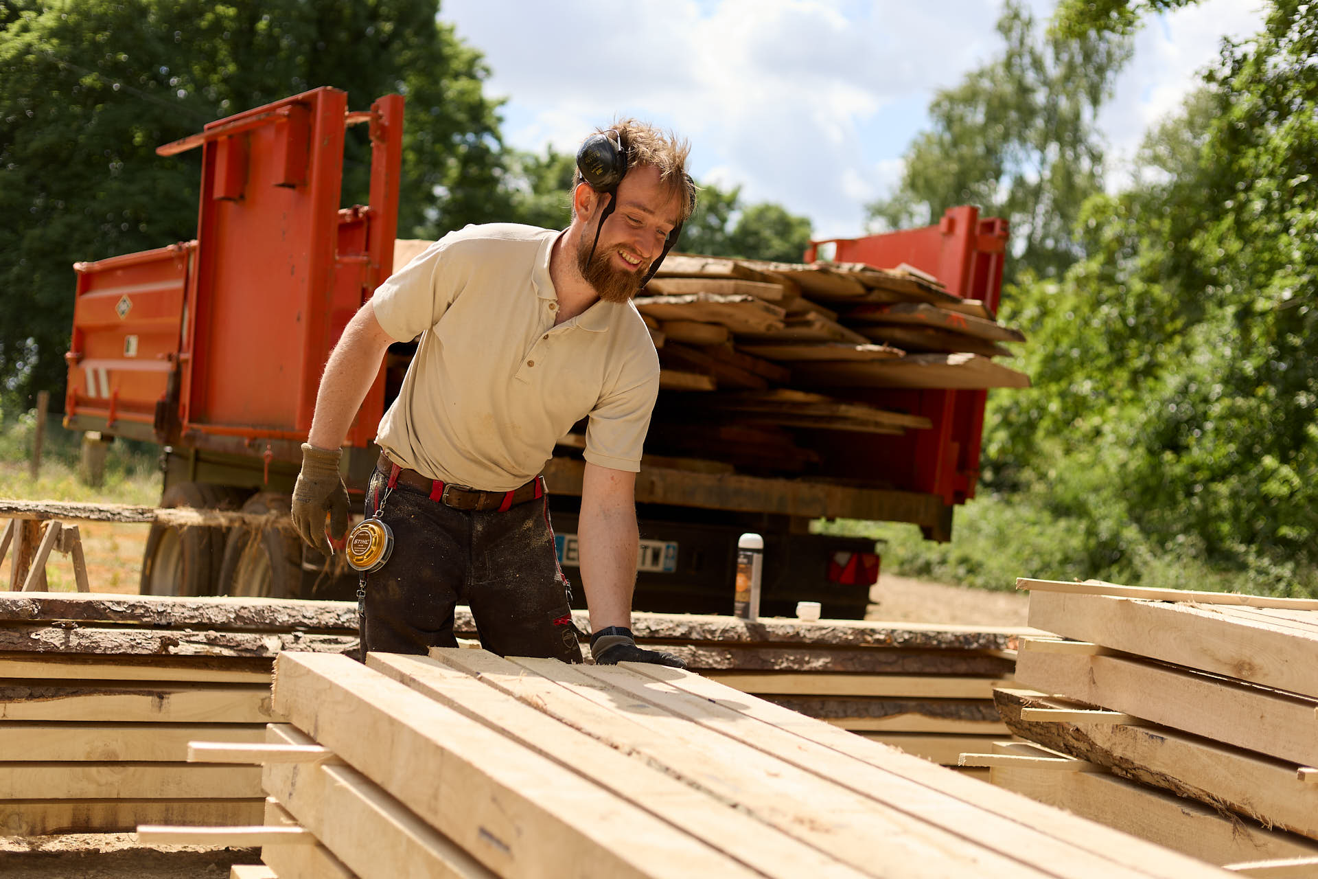 Gestionnaire forestier en action portant du bois valorisé en poteaux avec sa main lors d'un reportage sur l'exploitation forestière durable.