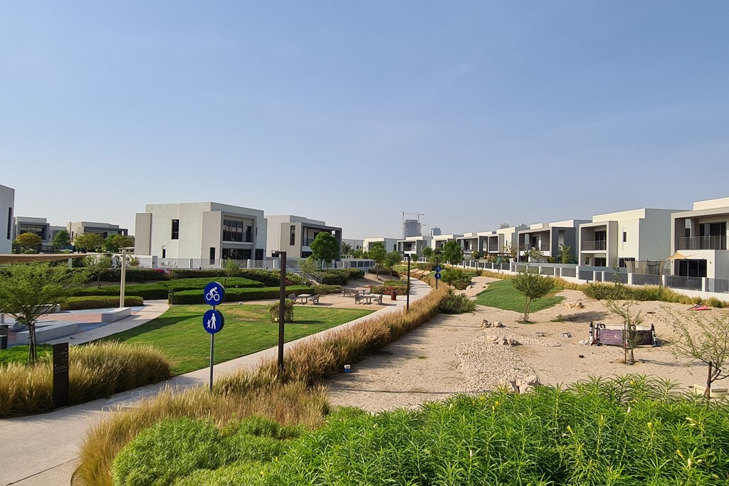 A modern residential area featuring lush grass and trees, showcasing the Sidra Villas community.